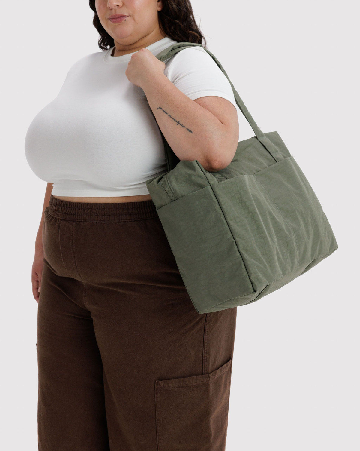 Olive green foldable duffel-style tote on a person, with side handles and zip pocket.
