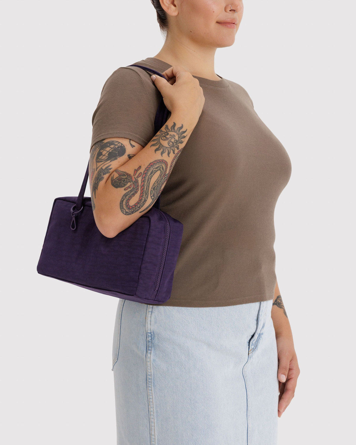 Deep purple nylon bowler bag with top zipper and short handles, held by model