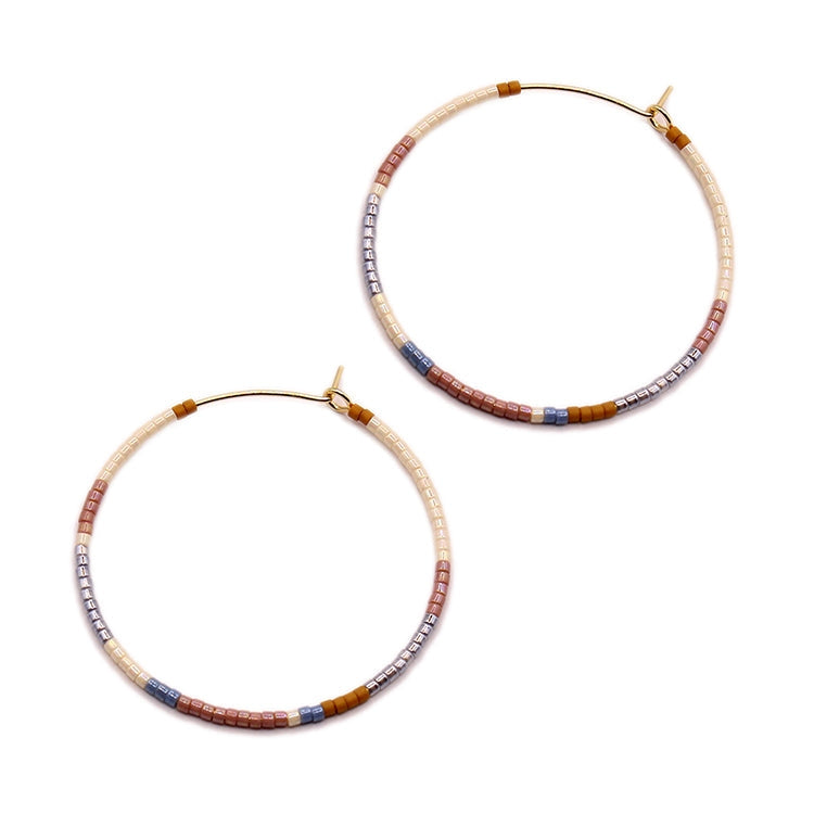 Gold-tone hoop earrings with neutral beaded cylinder accents, clasp backs visible
