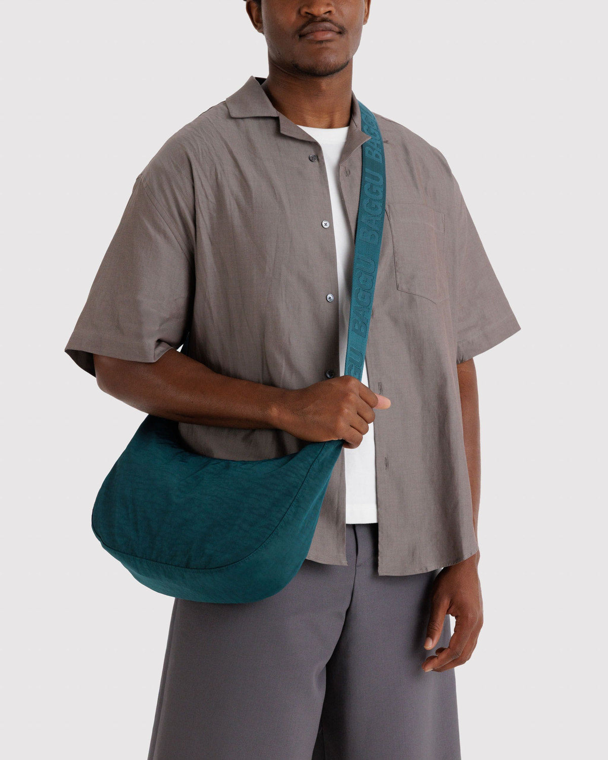 Teal nylon crescent bag worn crossbody on model