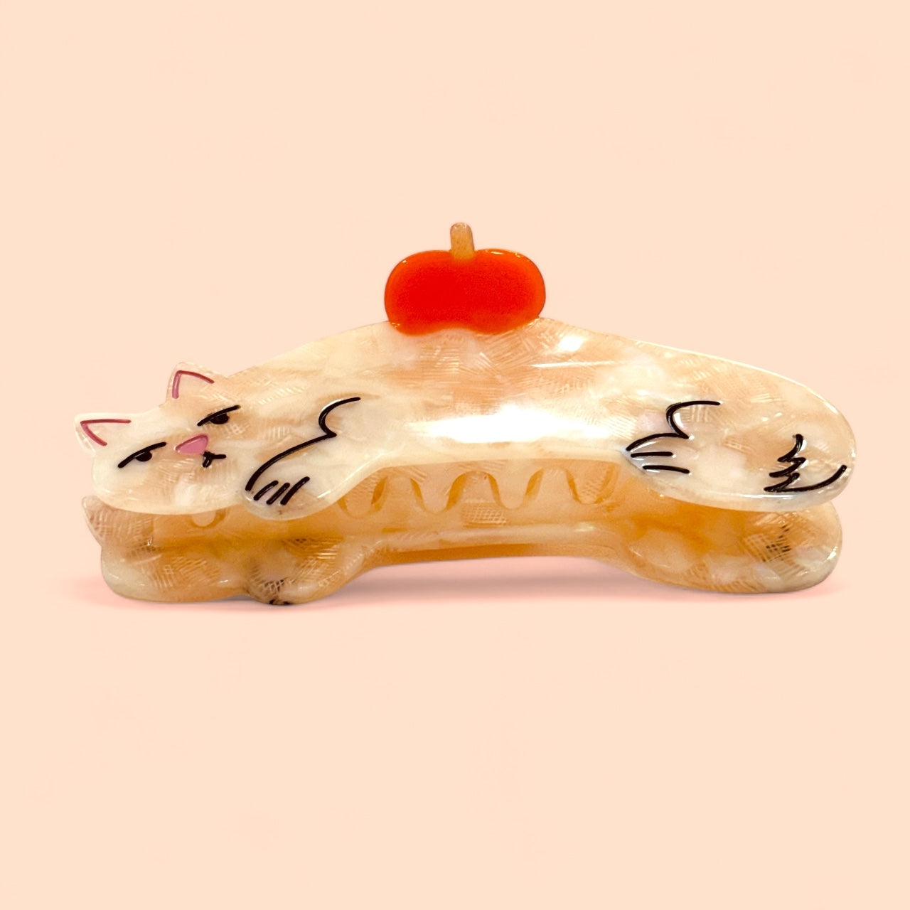 Cream cat hair claw with orange top, curved shape and smiling kitty face