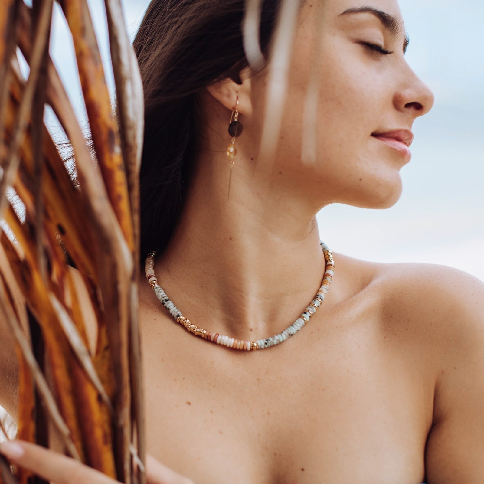 Beaded gold-tone necklace resting at collarbone with light blue/gray and gold beads