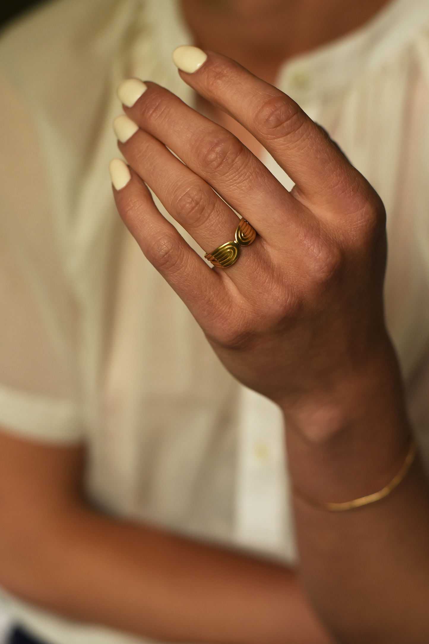 Gold sculpted double-arc ring on finger, side spiral with domed arc design