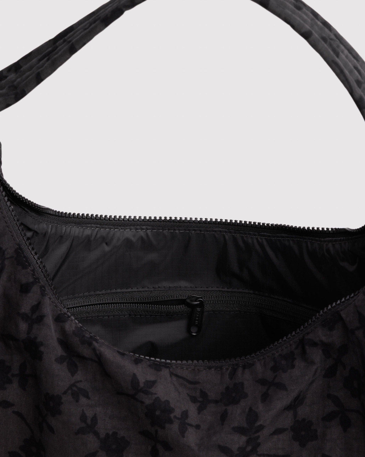 Black nylon shoulder bag with all-over dark floral pattern and zip top opening.