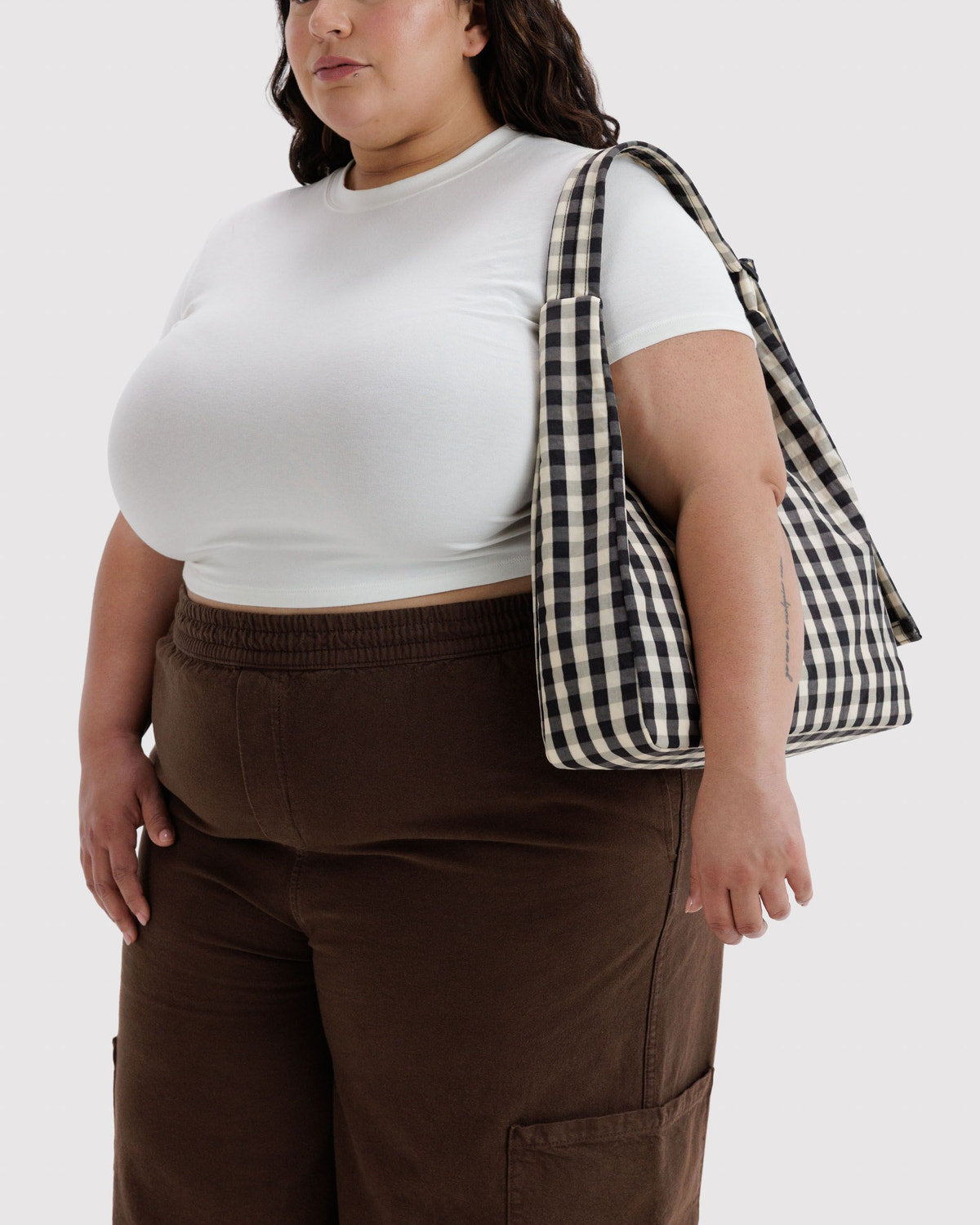 Nylon shoulder bag in brown with wide strap, side pocket, and top zipper seam.