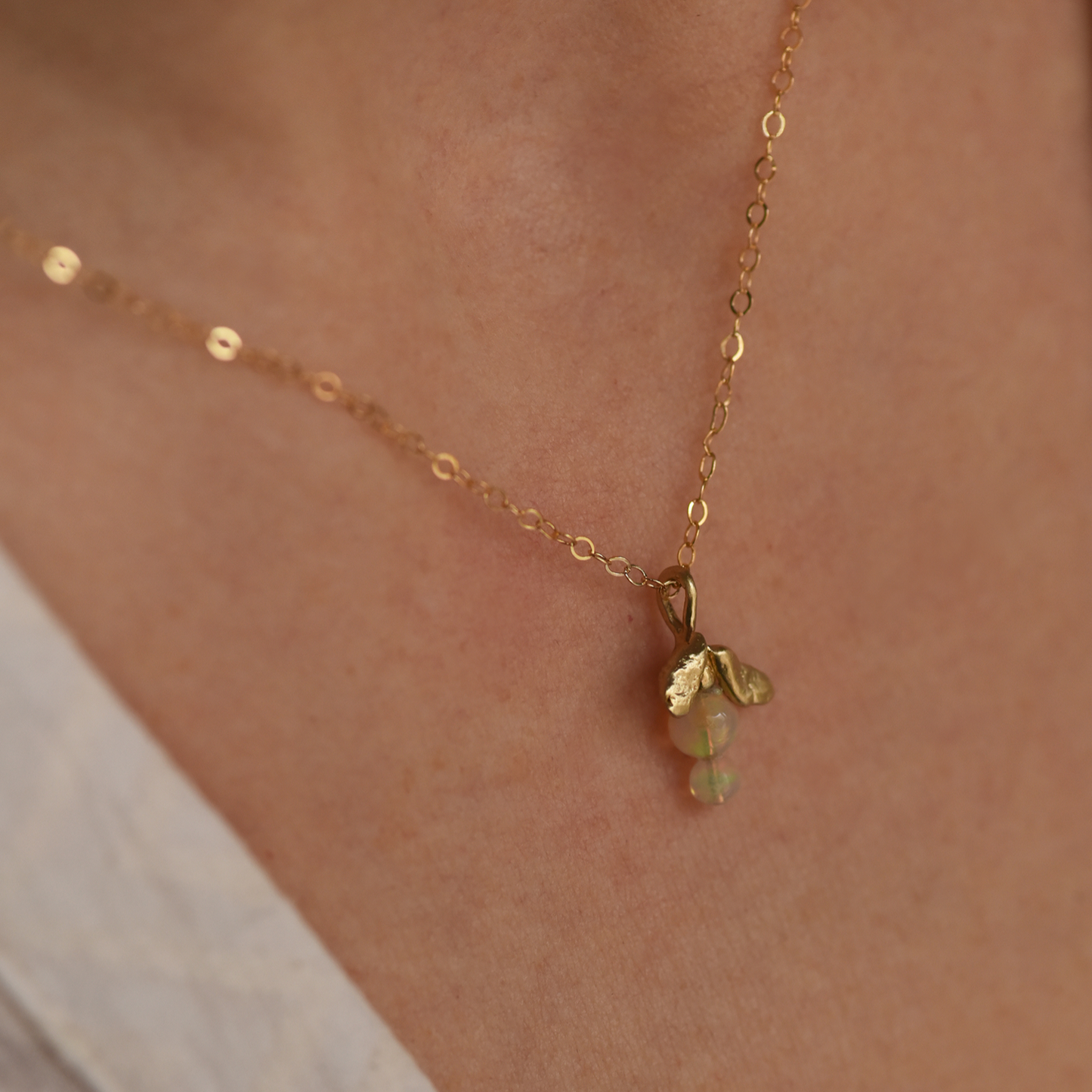 Gold leaf drop necklace with opal-like green pendant on a fine chain