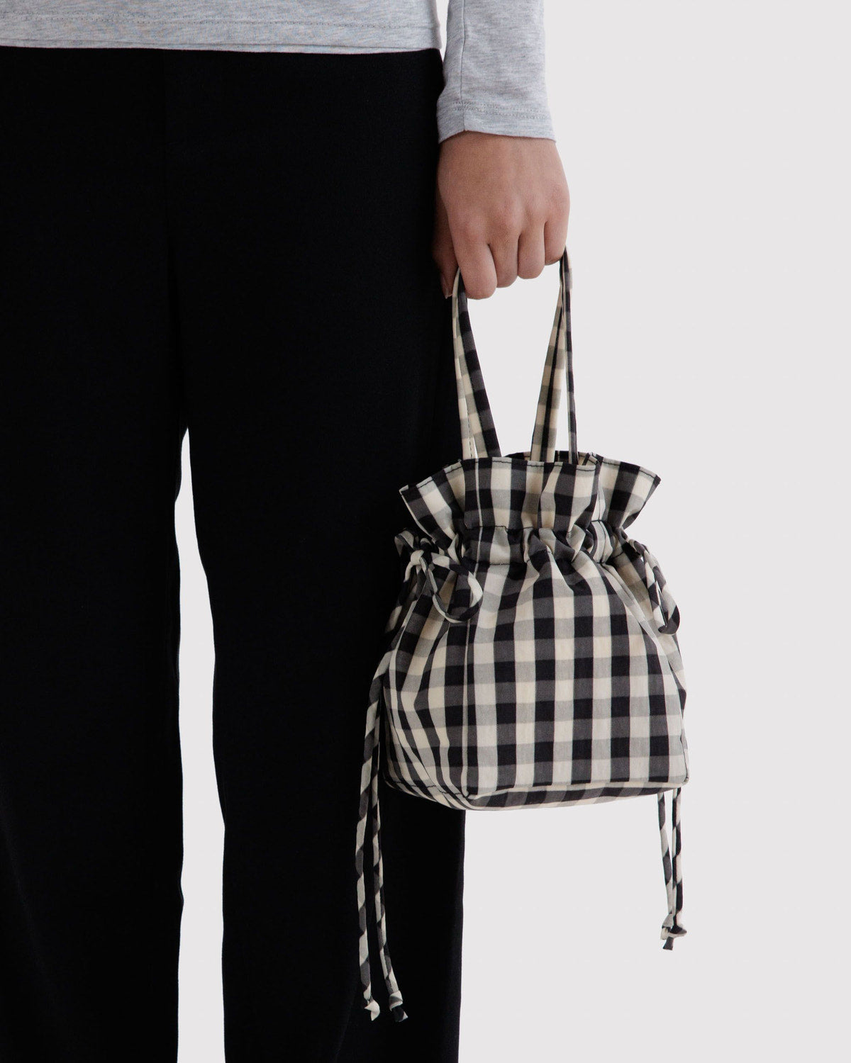 Black and cream gingham nylon drawstring bag held by side with cords