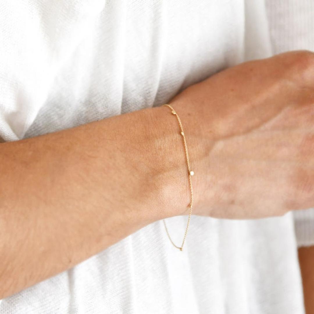 14-karat gold bracelet with small round charm beads on wrist