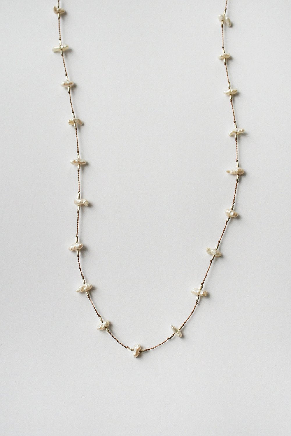Long keshi pearl necklace, close-up of white drop pearls and gold-tone links
