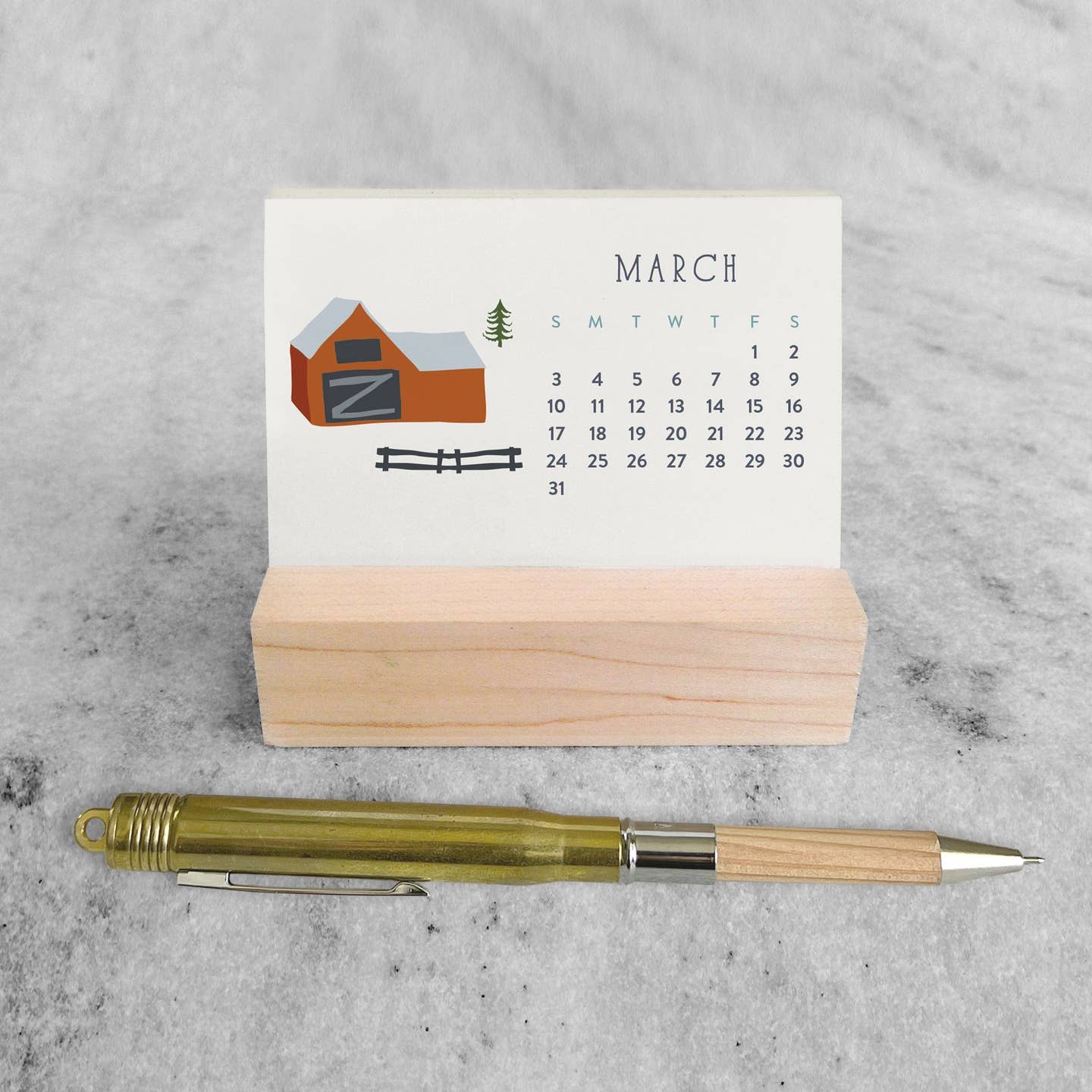 Mini desk calendar with March page, barn and fence illustration, wooden stand and pen