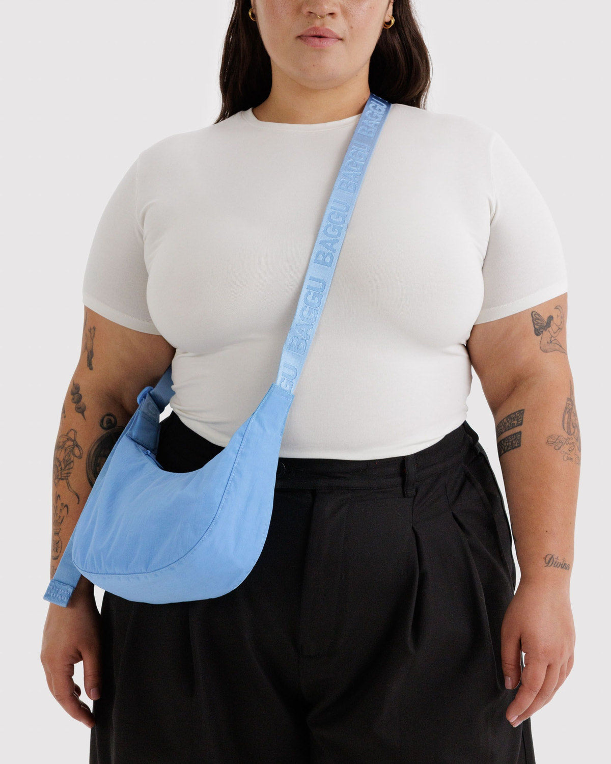 Small nylon crescent bag in light blue worn crossbody with webbing strap