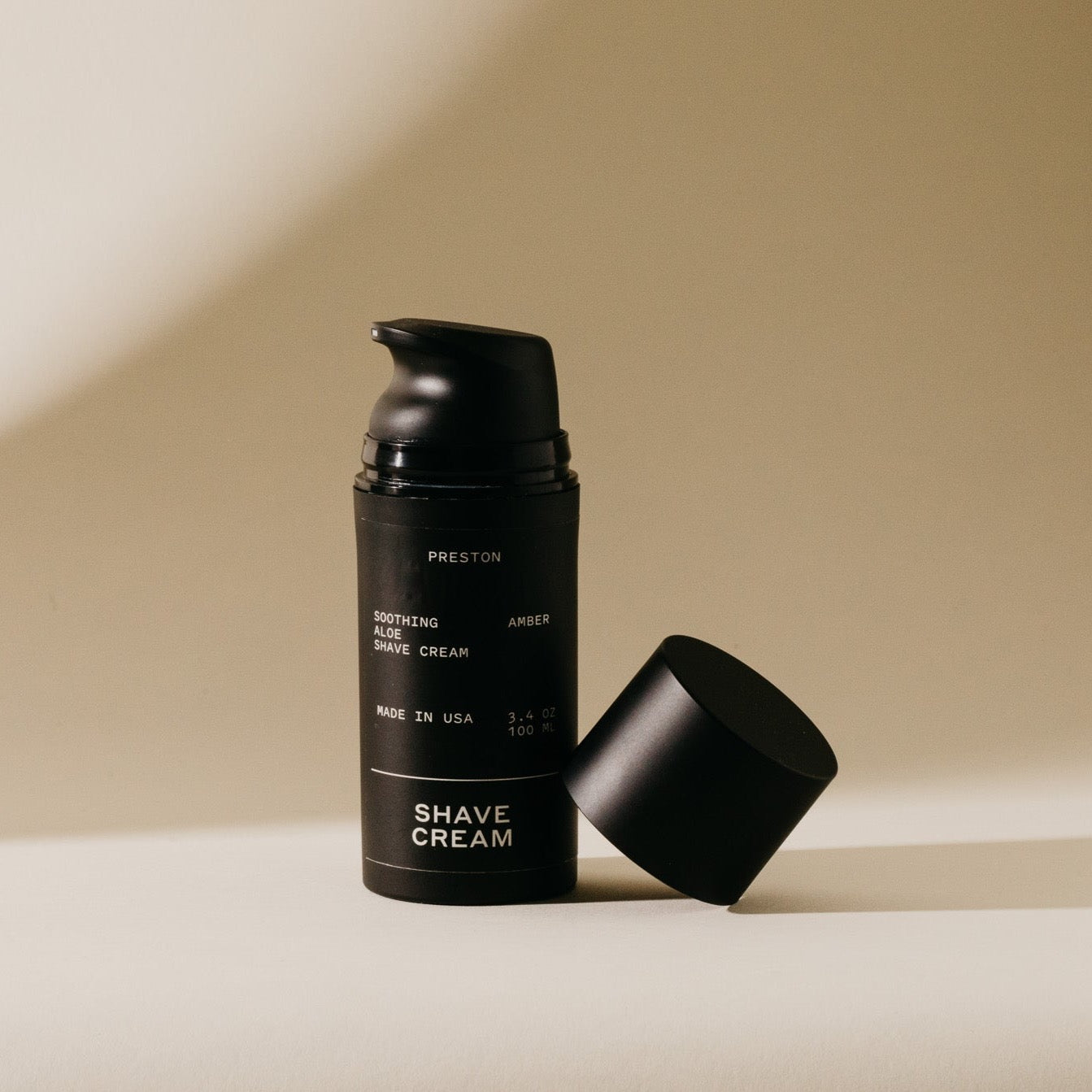 Shave cream aerosol canister with open cap, black bottle labeled PRESTON and AMBER