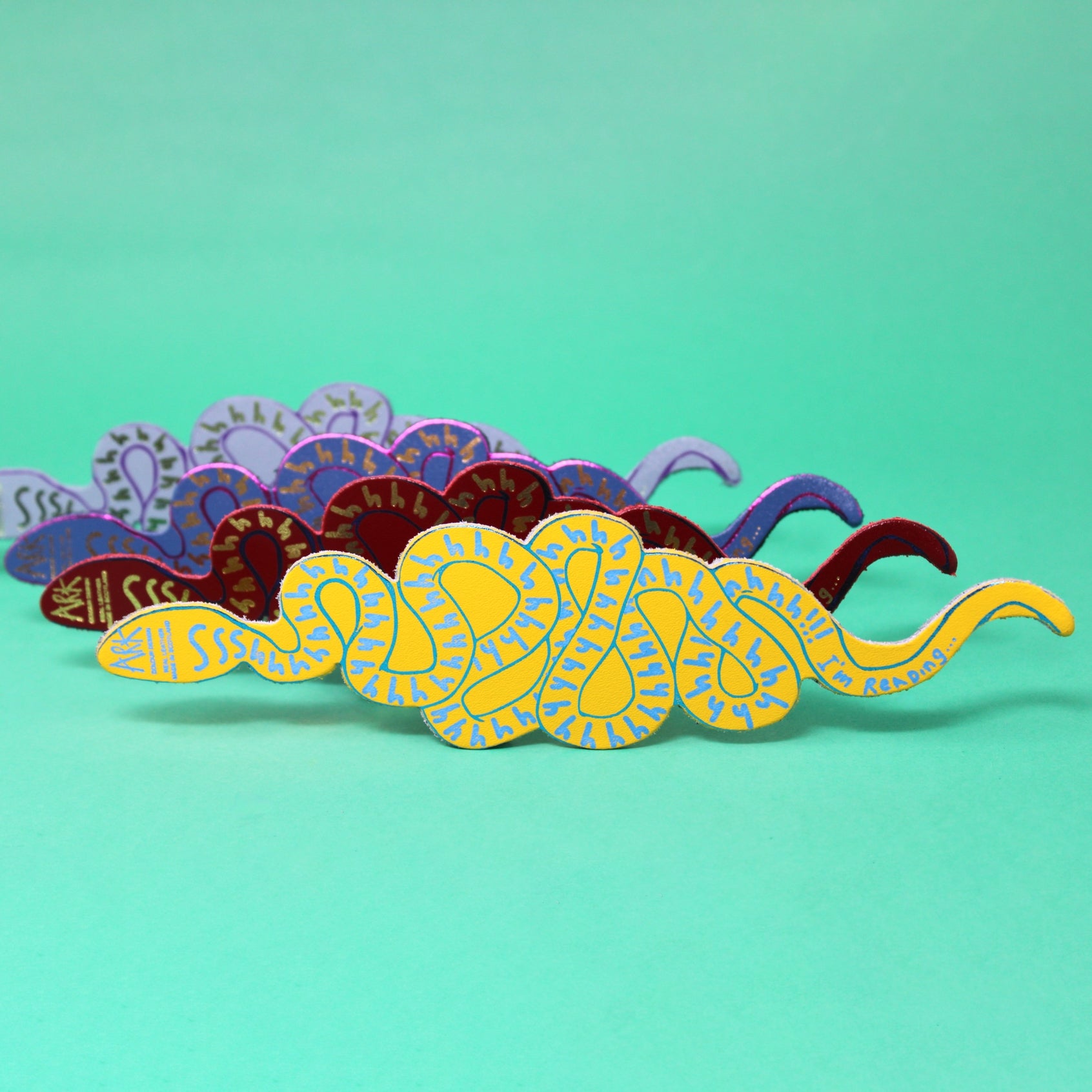 Stack of coiled snake bookmarks in yellow, purple, red, and gray with wavy pattern