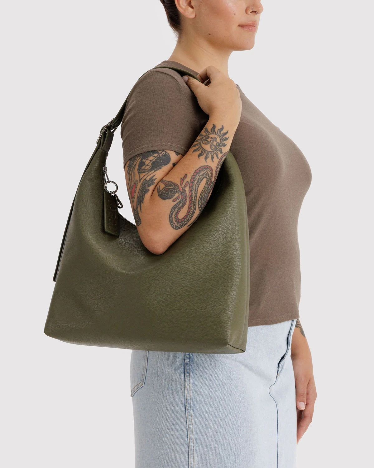 Olive green recycled leather shoulder bag with side profile, top handle, and hanging charm