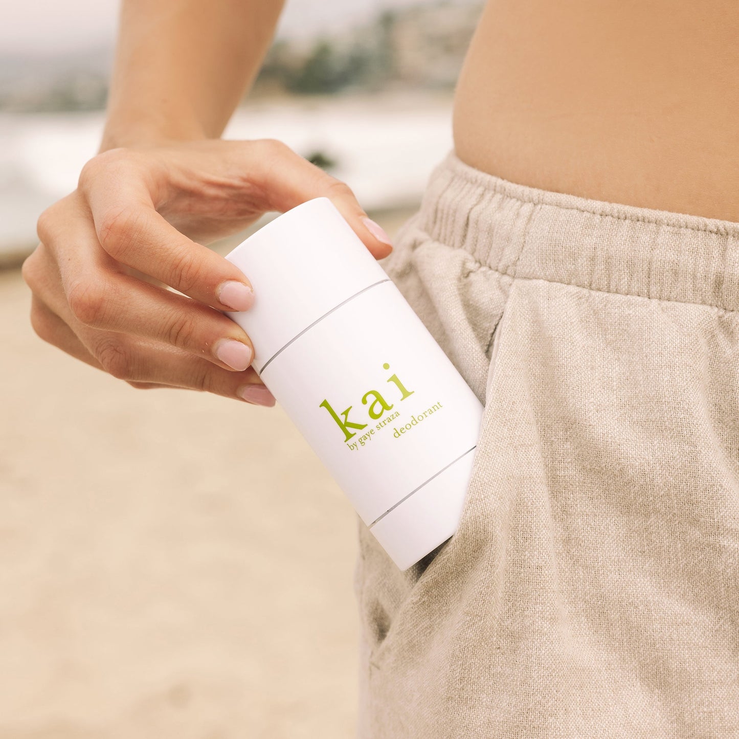 Kai deodorant stick, 2 oz, held in hand; white twist-up container