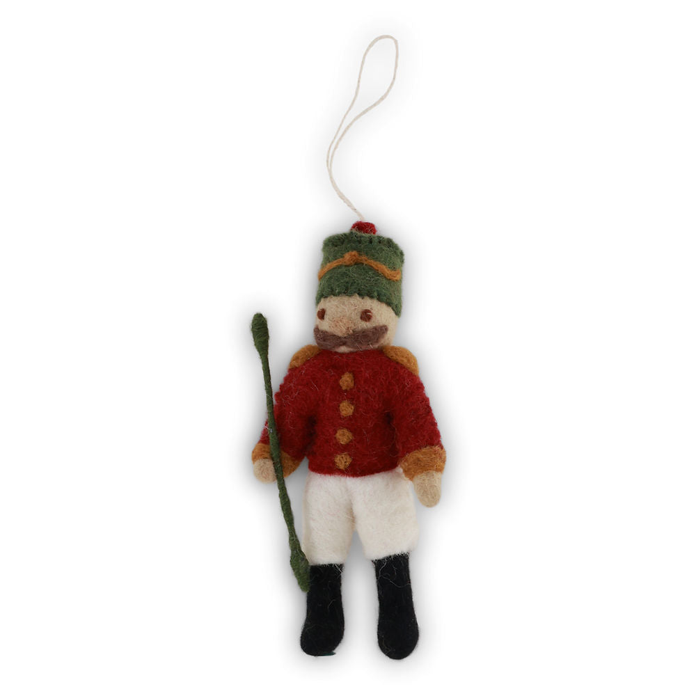 Felt nutcracker ornament with red coat, white pants, black boots, and green hat