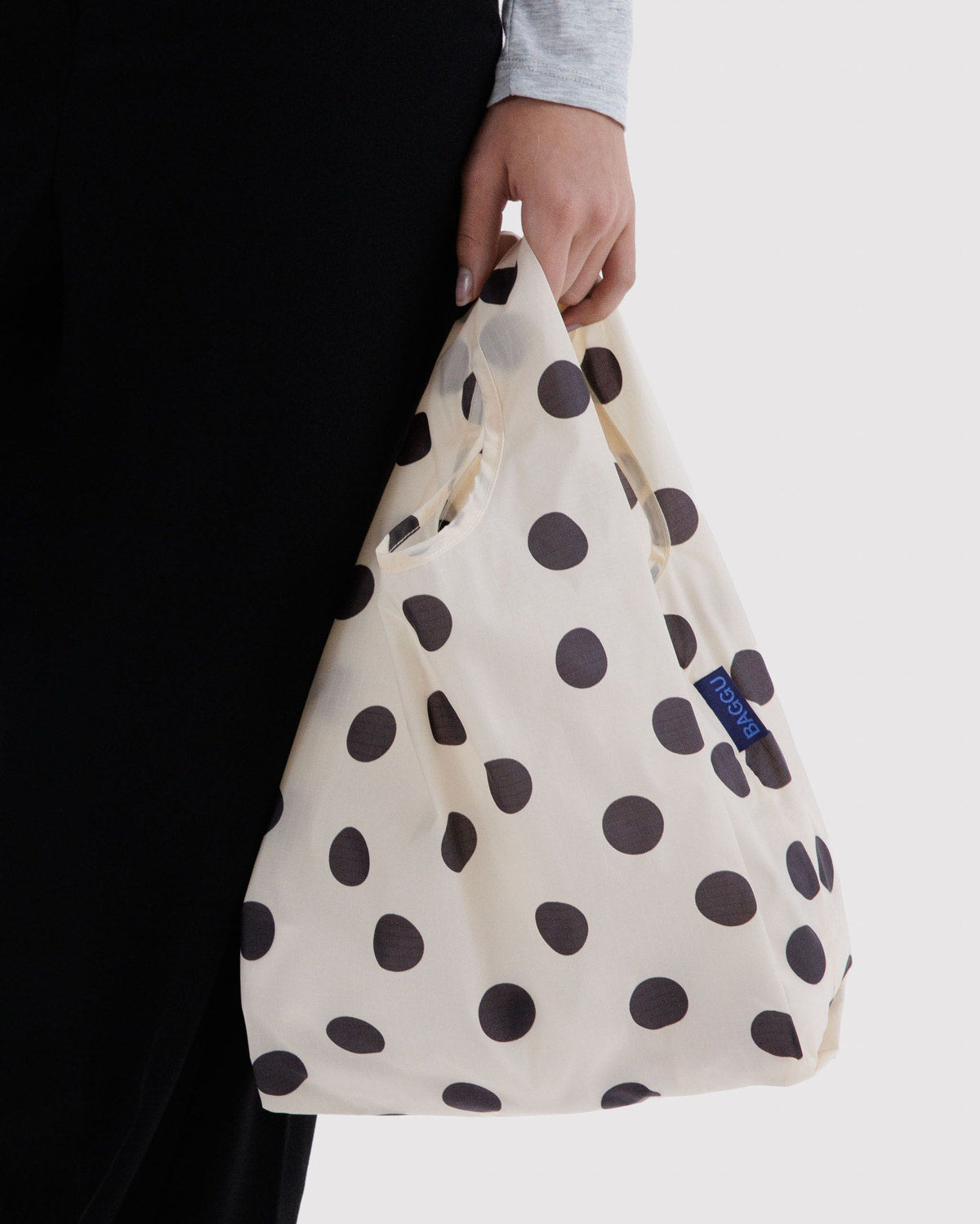 Reusable tote bag in off-white with large dark polka dots, short handles