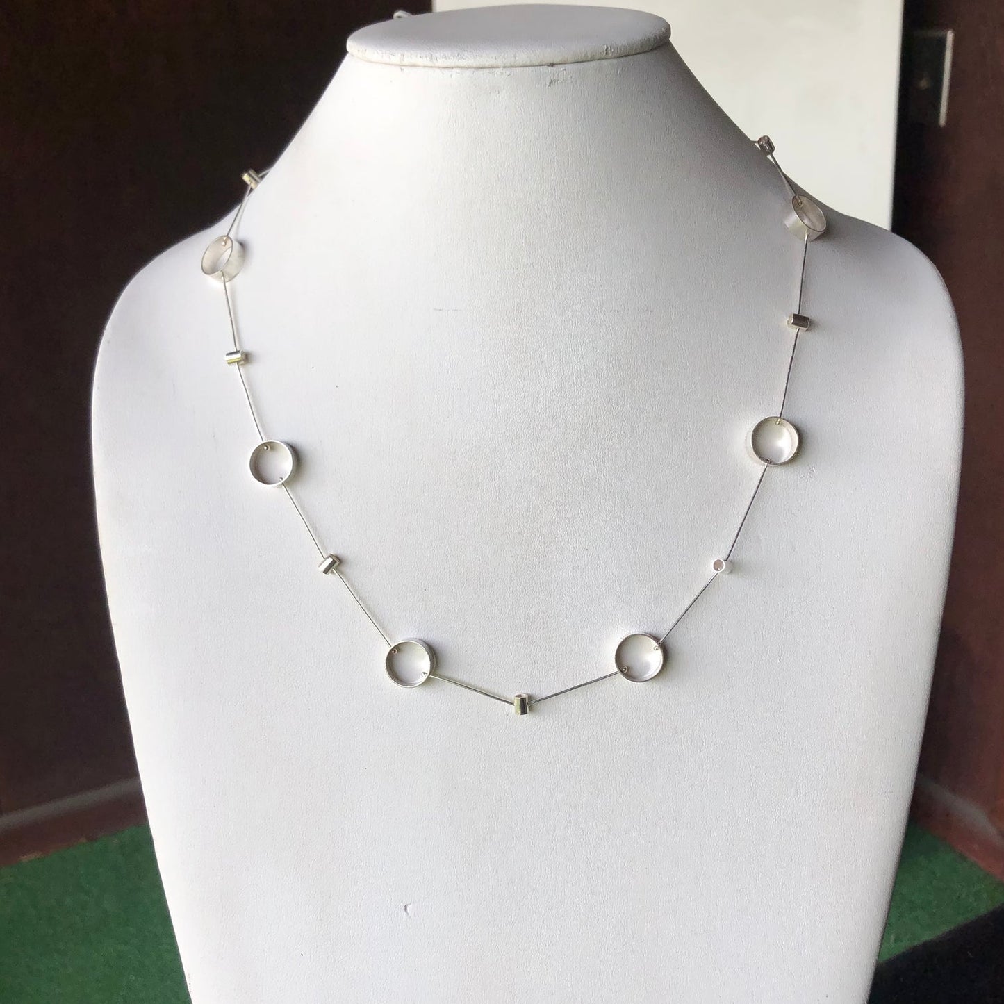 Silver-tone disc-link tube pivot necklace on mannequin bust