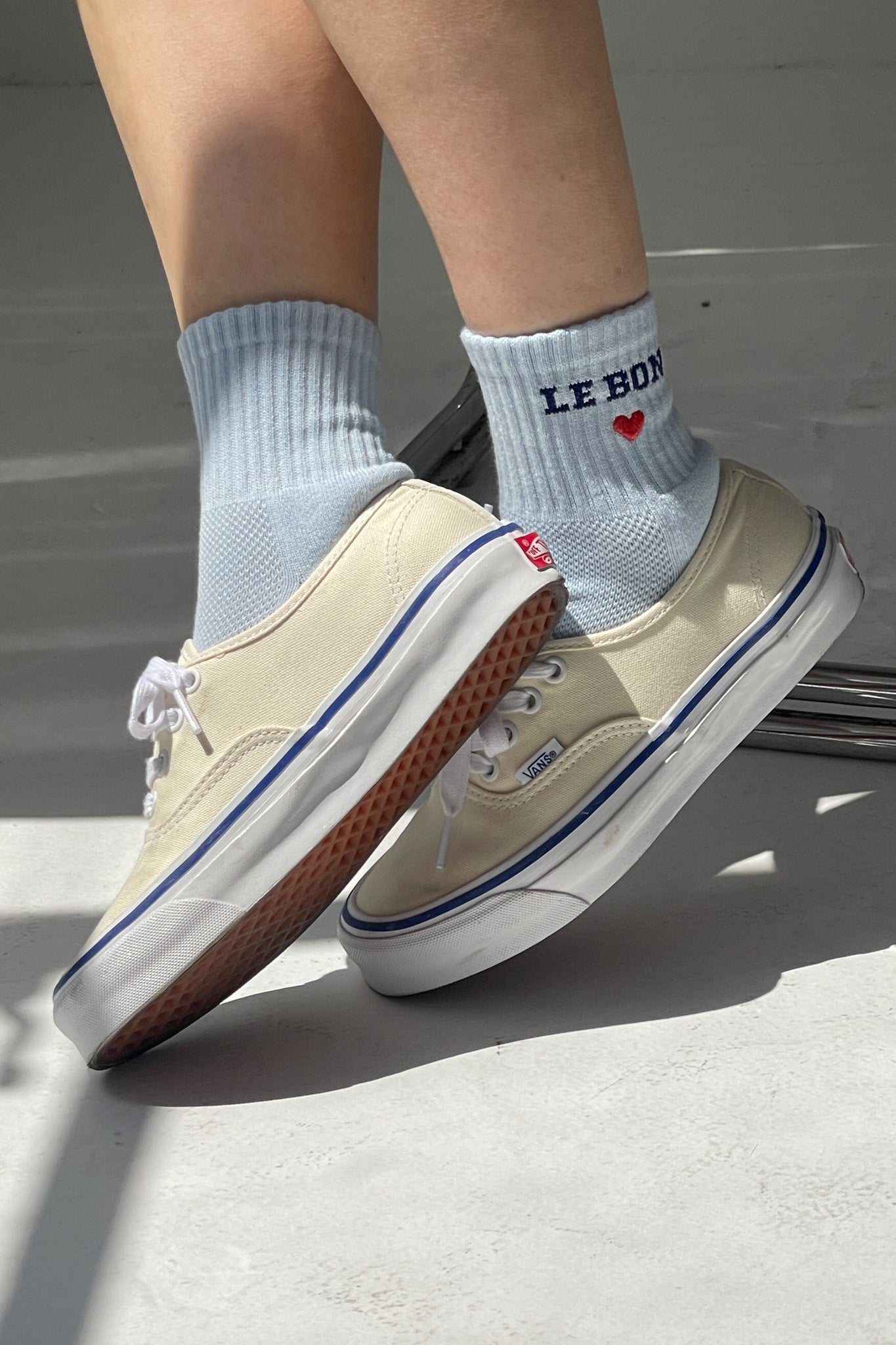Sky blue crew socks with LE BON cuff embroidery and red heart, worn with sneakers