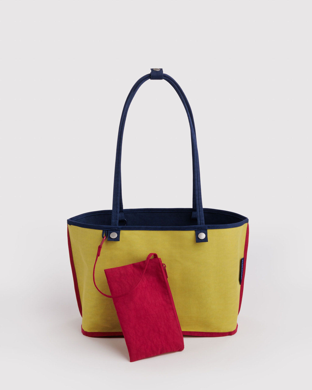 Medium reversible nylon tote with top handles, navy with yellow side and red pouch.