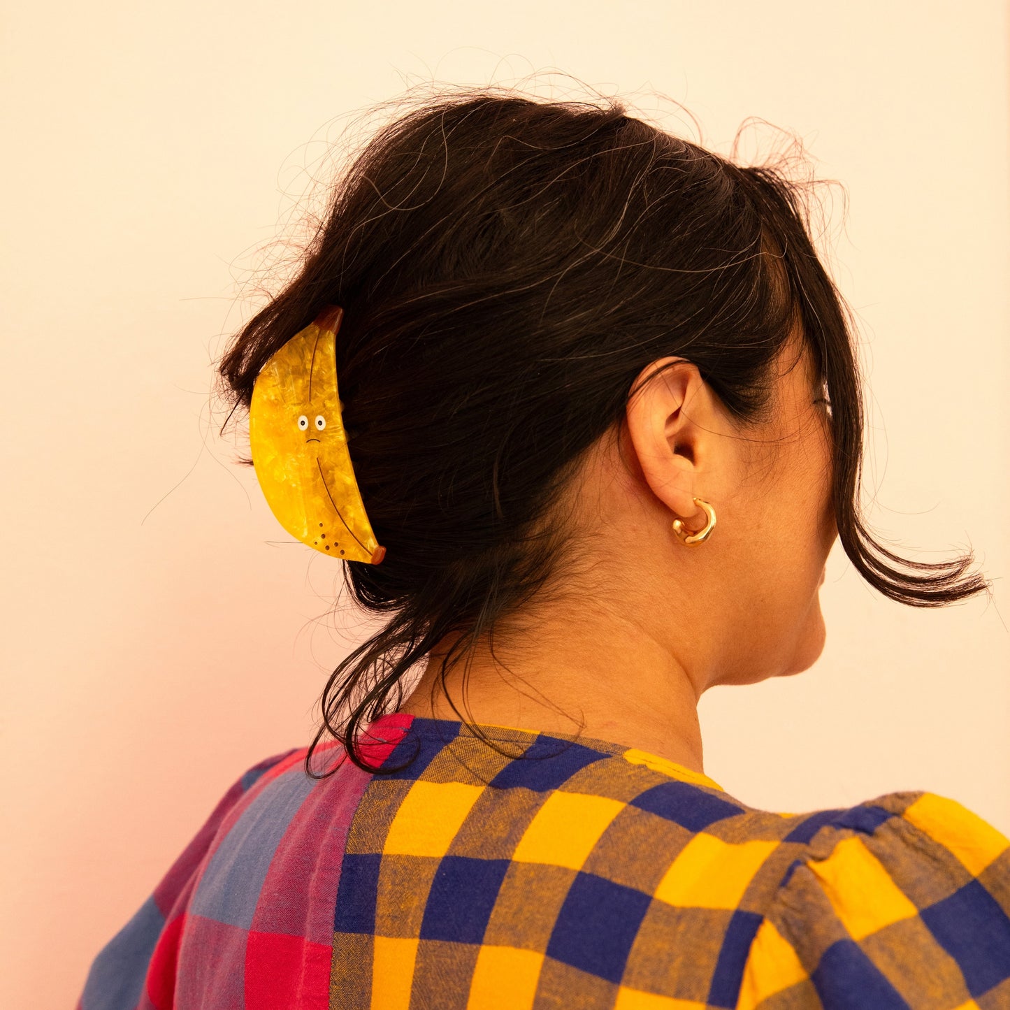 Yellow banana-shaped hair claw clipped in dark hair, side view