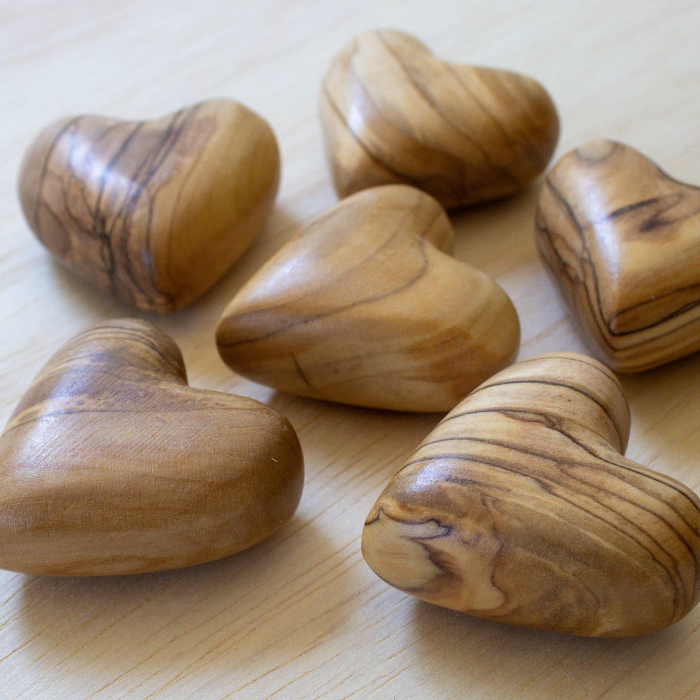 Olive wood heart-shaped carved pieces, close-up of natural brown hearts with wood grain.