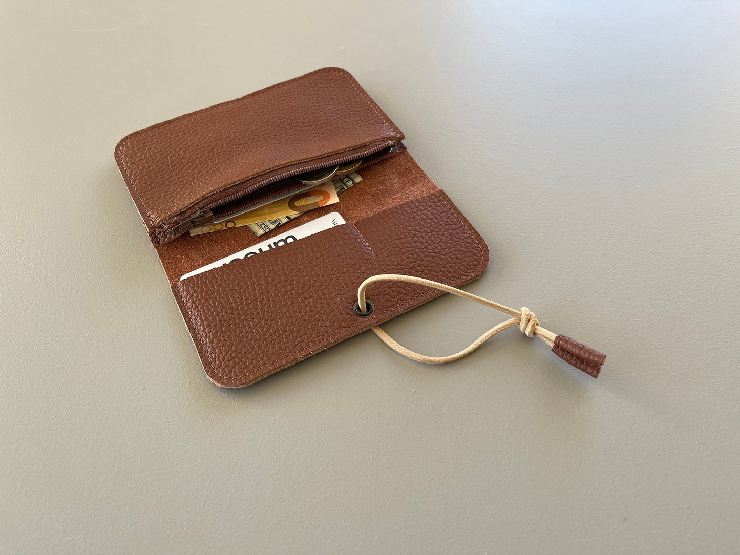 Brown leather knot wallet with flap open, showing card slots and lace cord tie