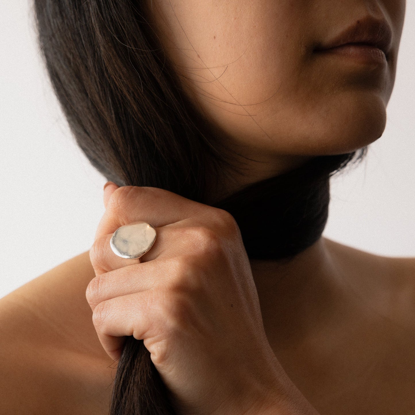 Silver hammered round ring close-up on finger, textured face