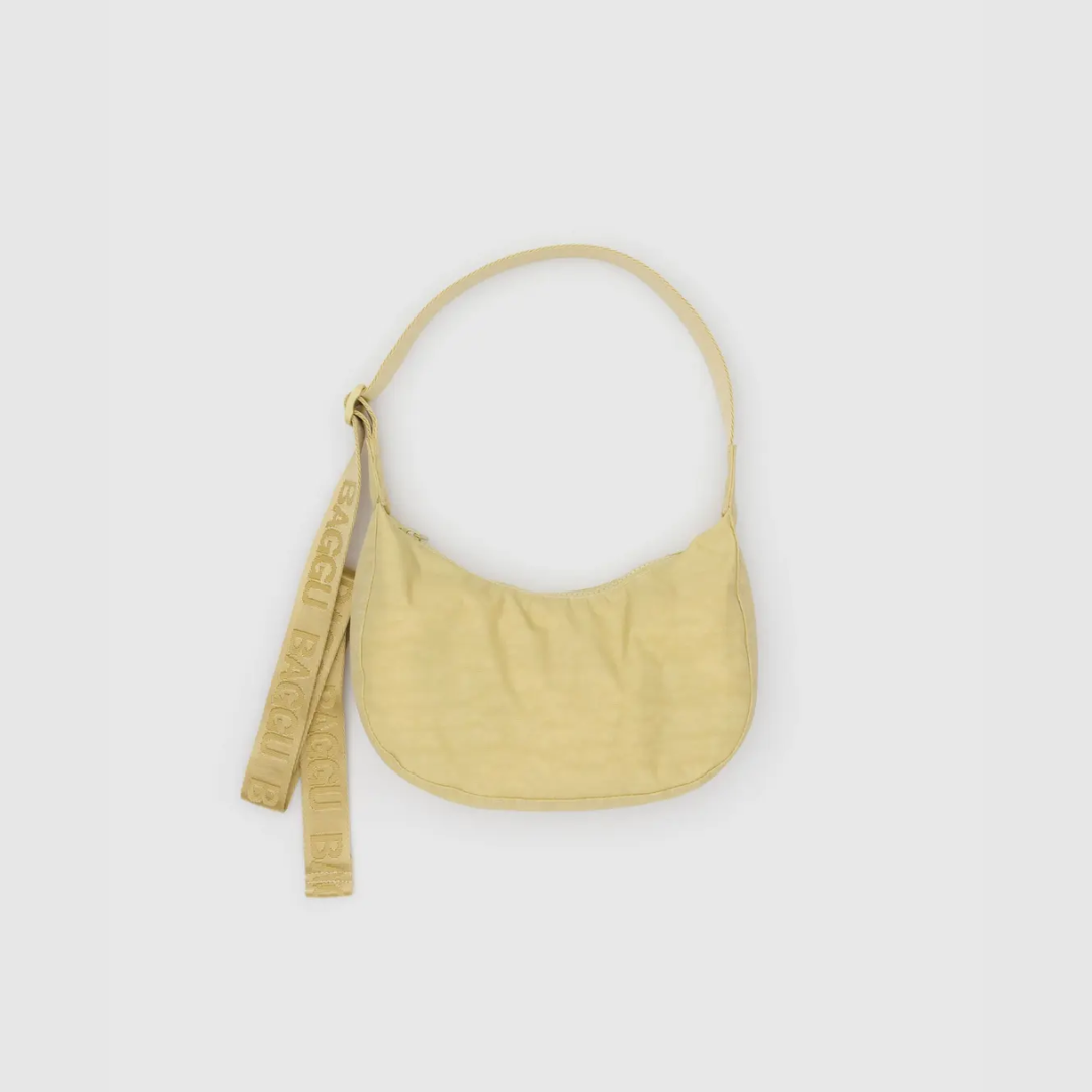 Small crescent nylon crossbody bag in pale yellow with curved strap and hanging tag