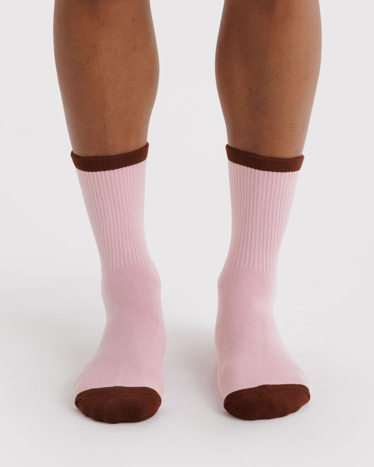 Ribbed blush pink socks on feet with dark brown cuff and rounded toe.