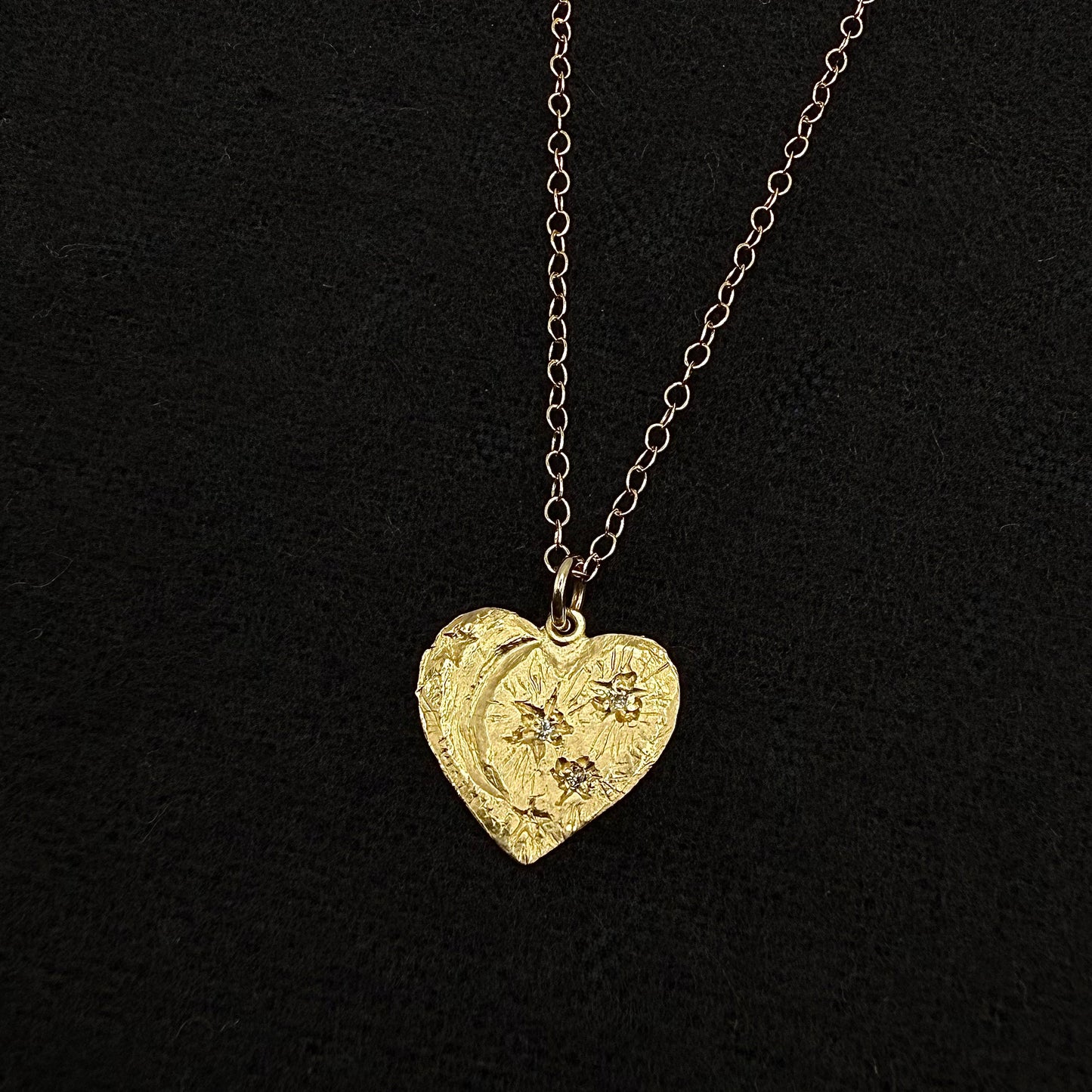 Gold heart pendant with star accents, hanging on linked chain