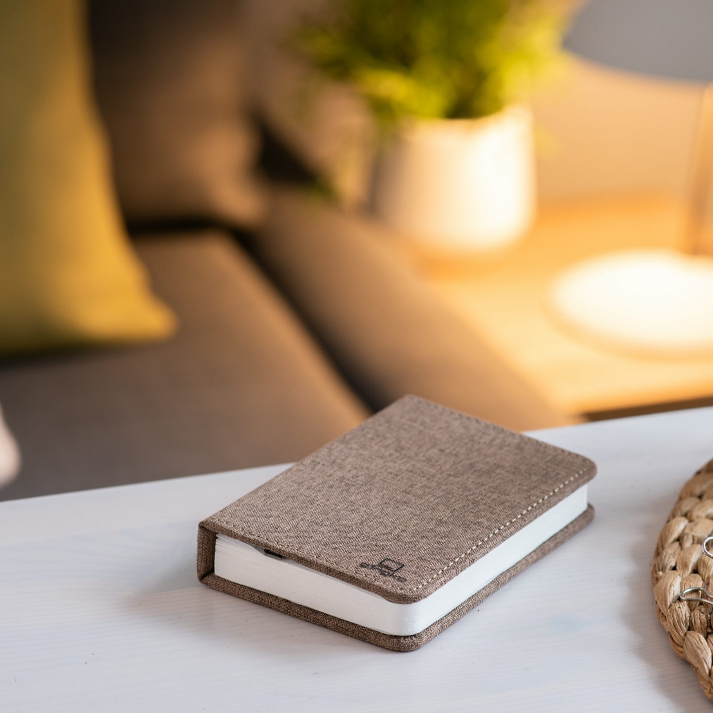 Gray linen smart booklight with folded cover on a table, warm light behind it