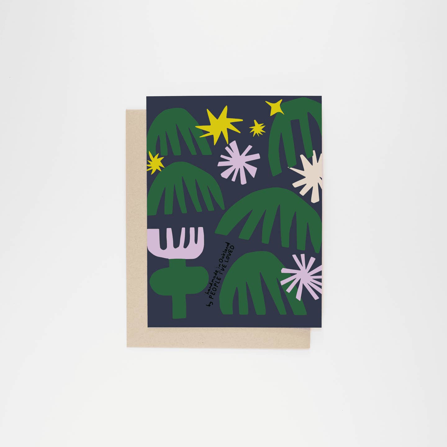 Greeting card front with green cacti and leaves, yellow moon, and purple starburst flowers.