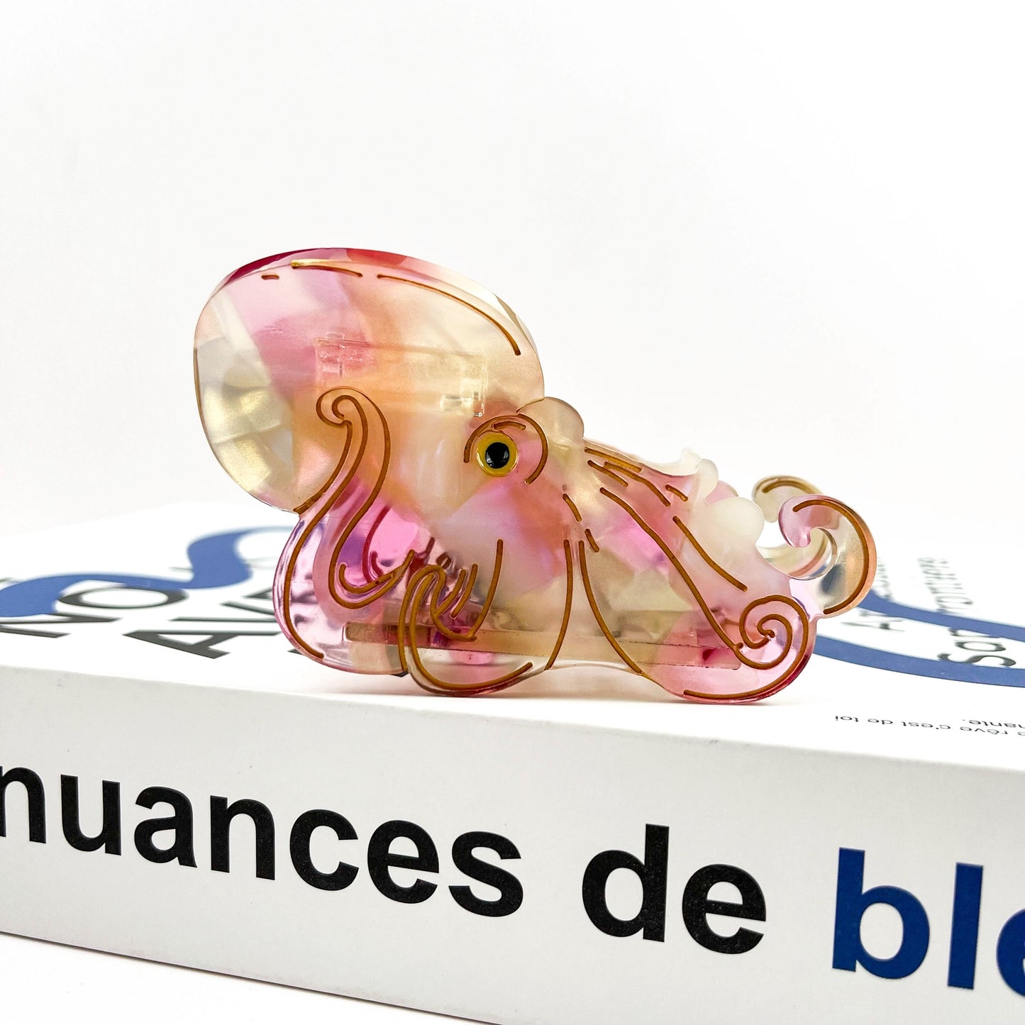 Translucent octopus claw clip with pink shell, curled tentacles, and gold eyes