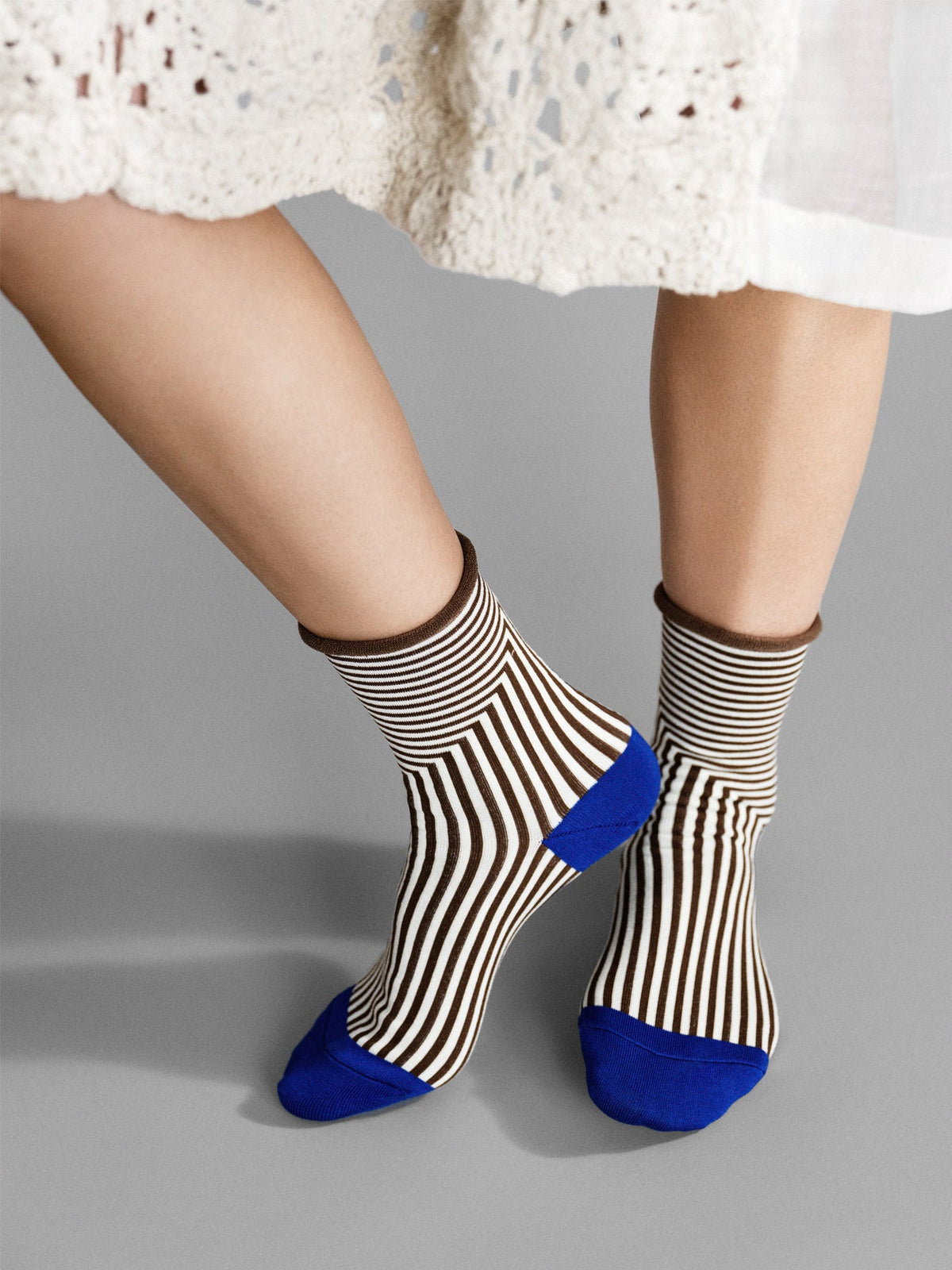 Brown-and-cream striped crew socks with blue toe and cuff, worn with bare legs