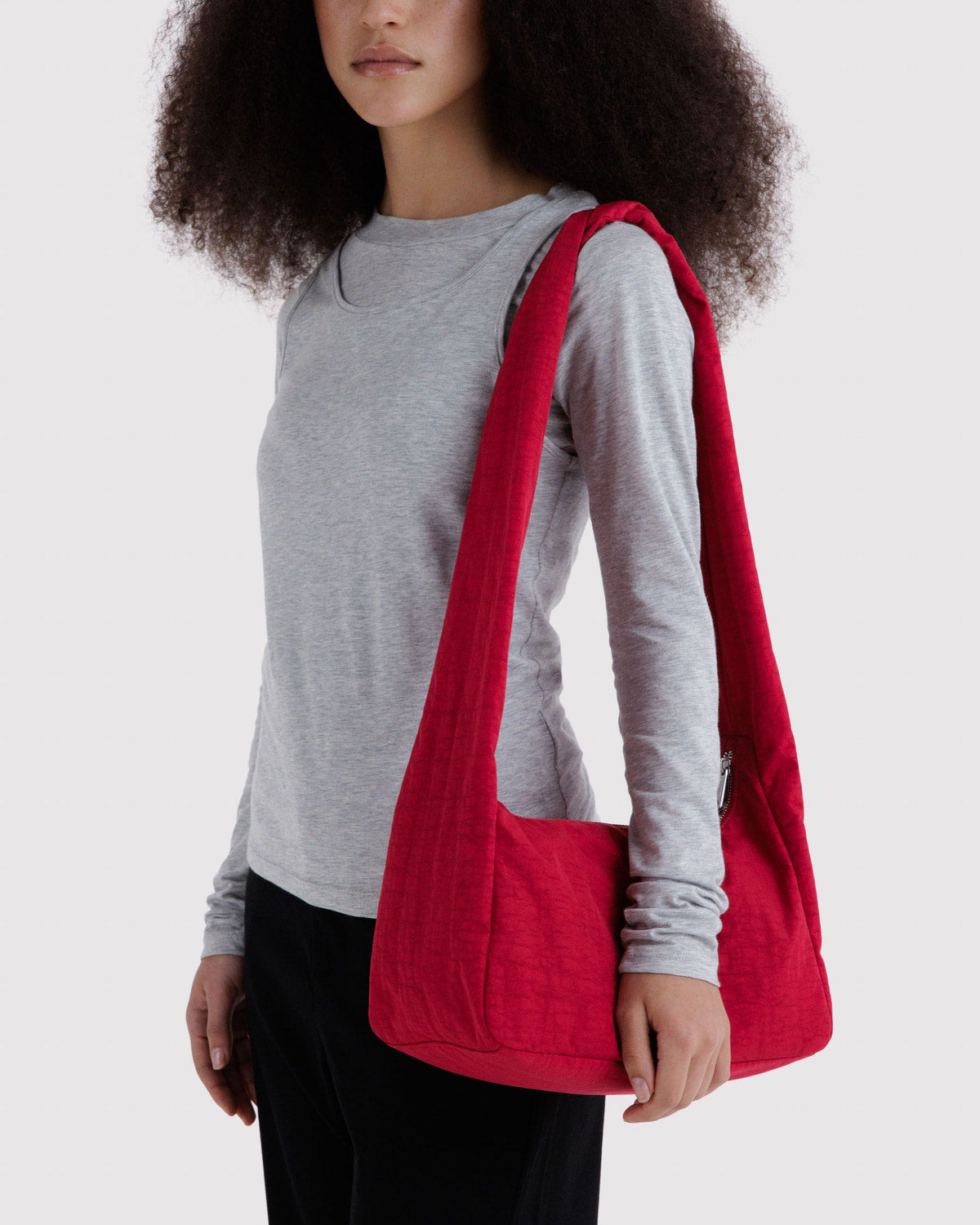 Red nylon shoulder bag with single handle, worn on shoulder with open top.