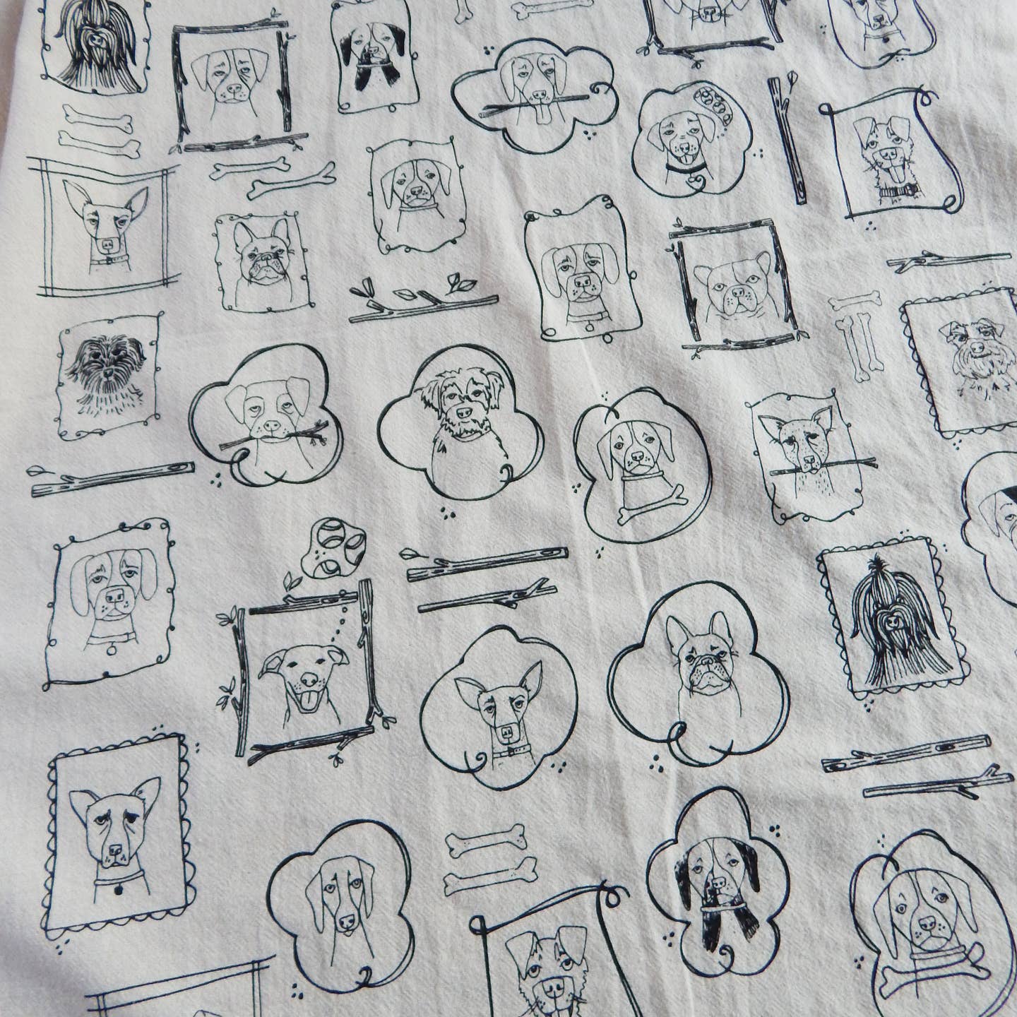 Dog kitchen tea towel with all-over line-drawn dog portraits, bowls, and utensils pattern.