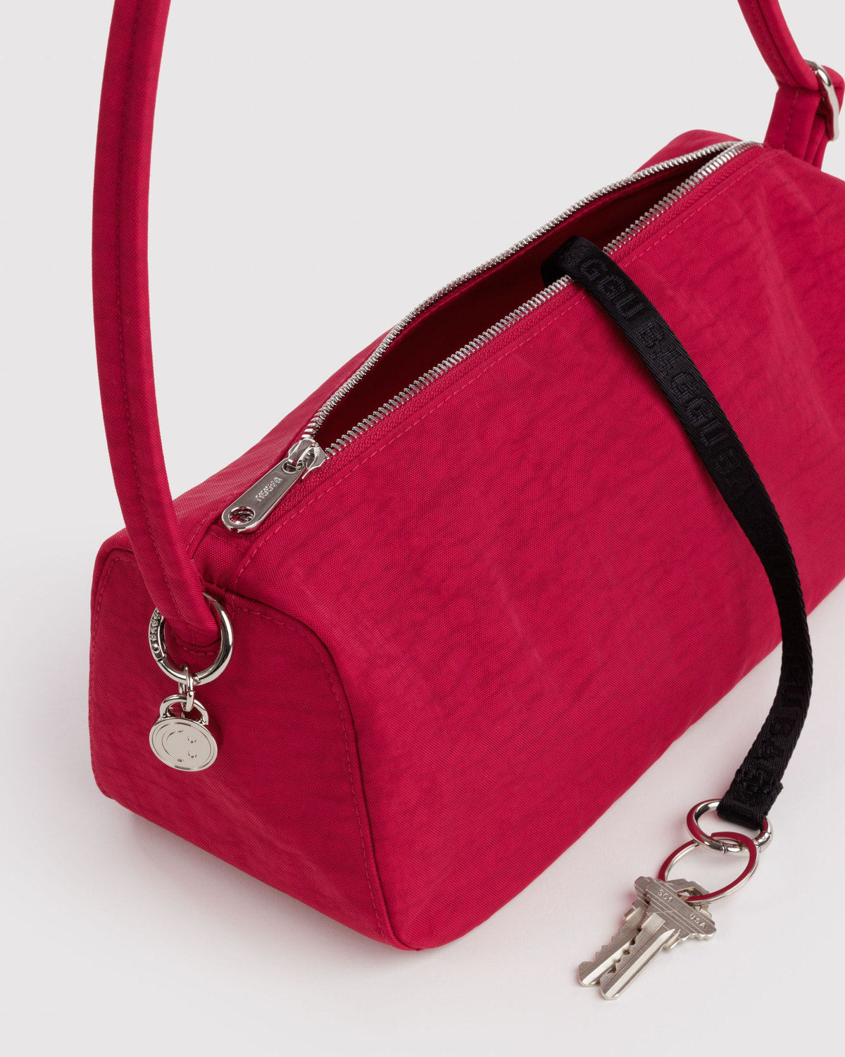 Red nylon loaf bag detail with front zipper, key charm, and crossbody strap