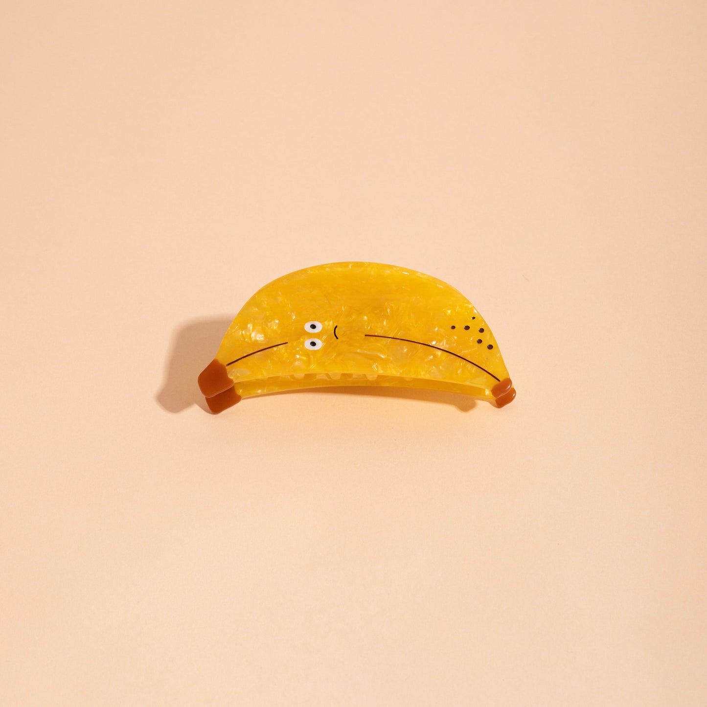 Yellow banana-shaped hair claw with button eyes and curved clamp