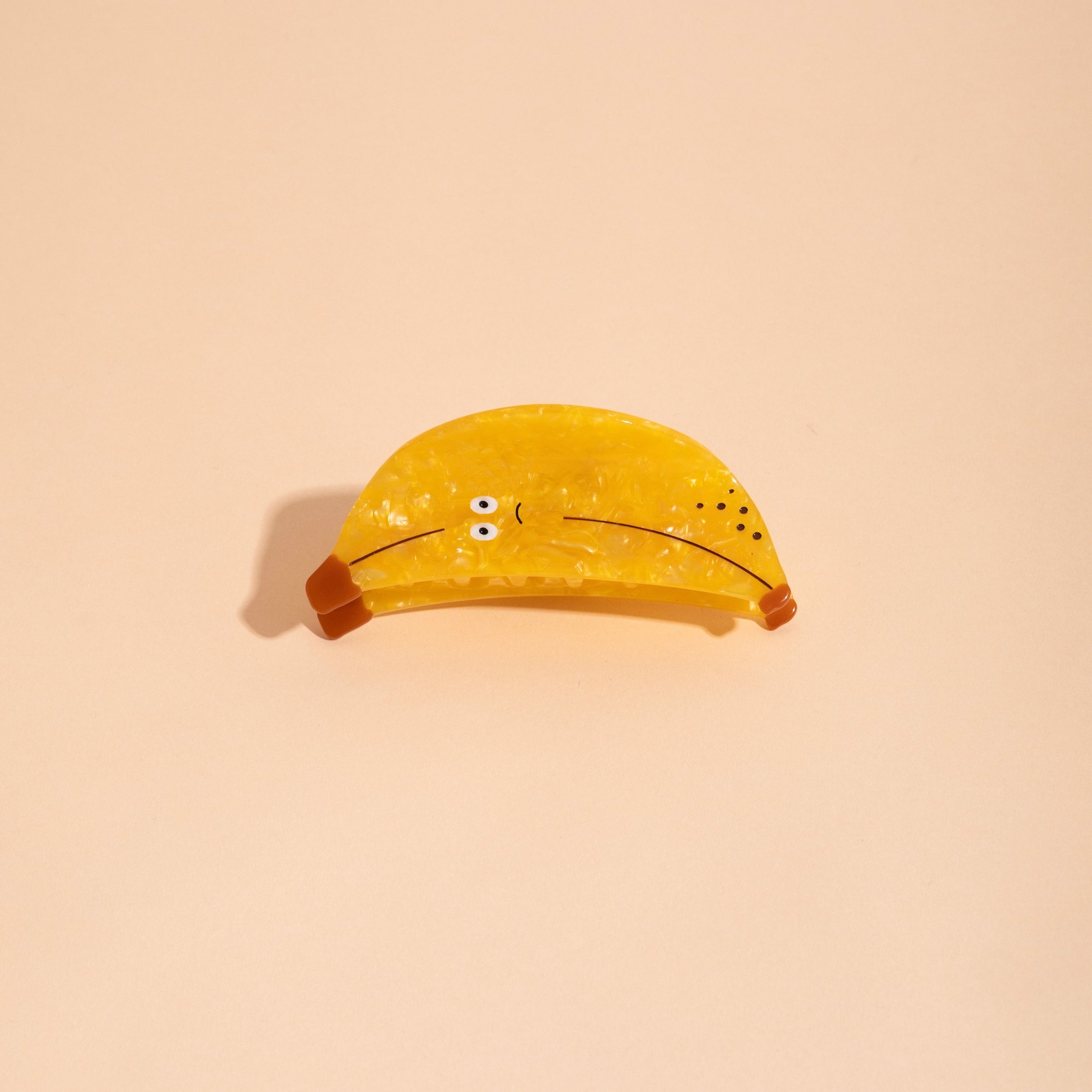 Yellow banana-shaped hair claw with button eyes and curved clamp