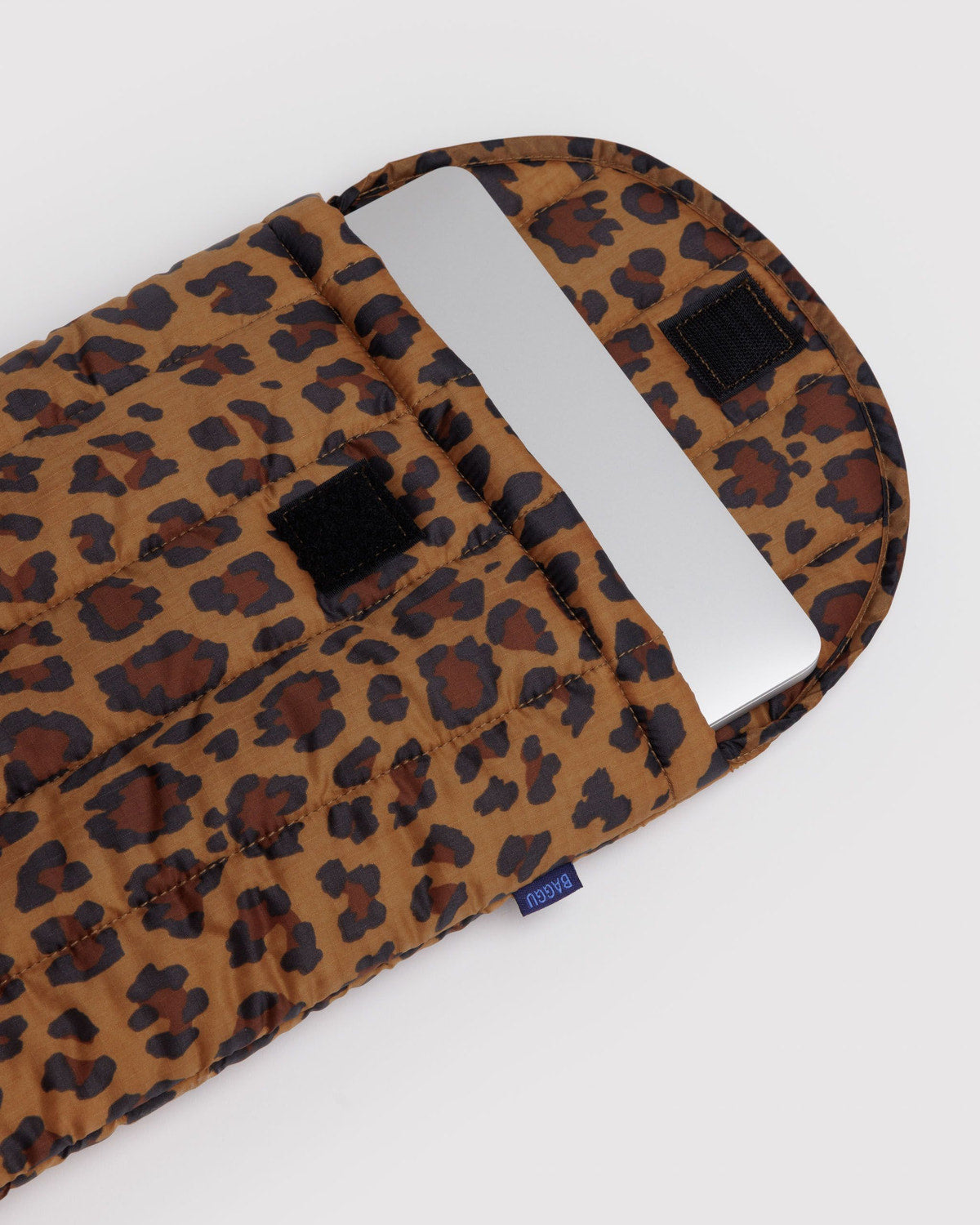 Leopard-print puffy 13"/14" laptop sleeve with black label tabs and carry-handle opening.