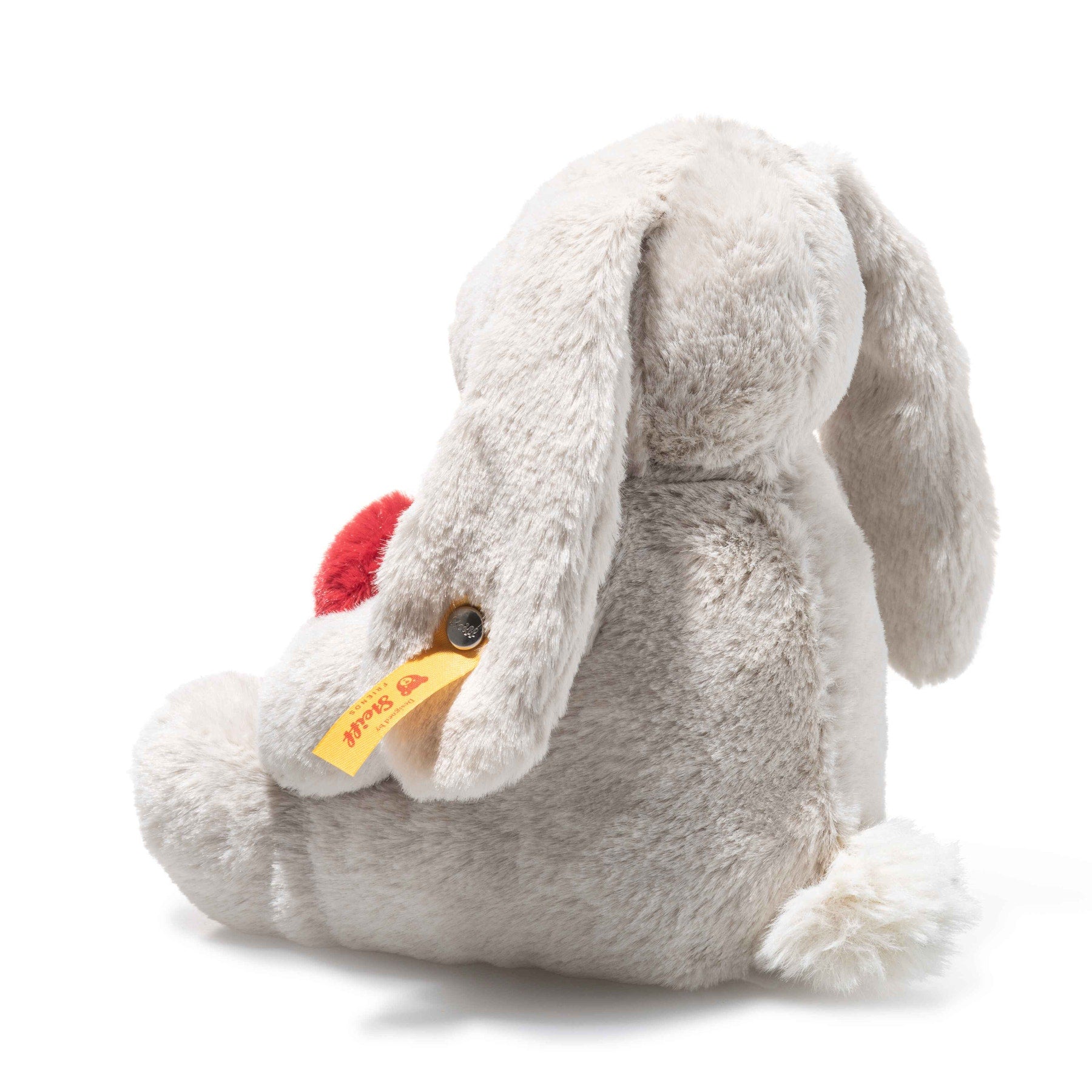 Sitting plush rabbit with red heart, light gray fur and yellow brand tag