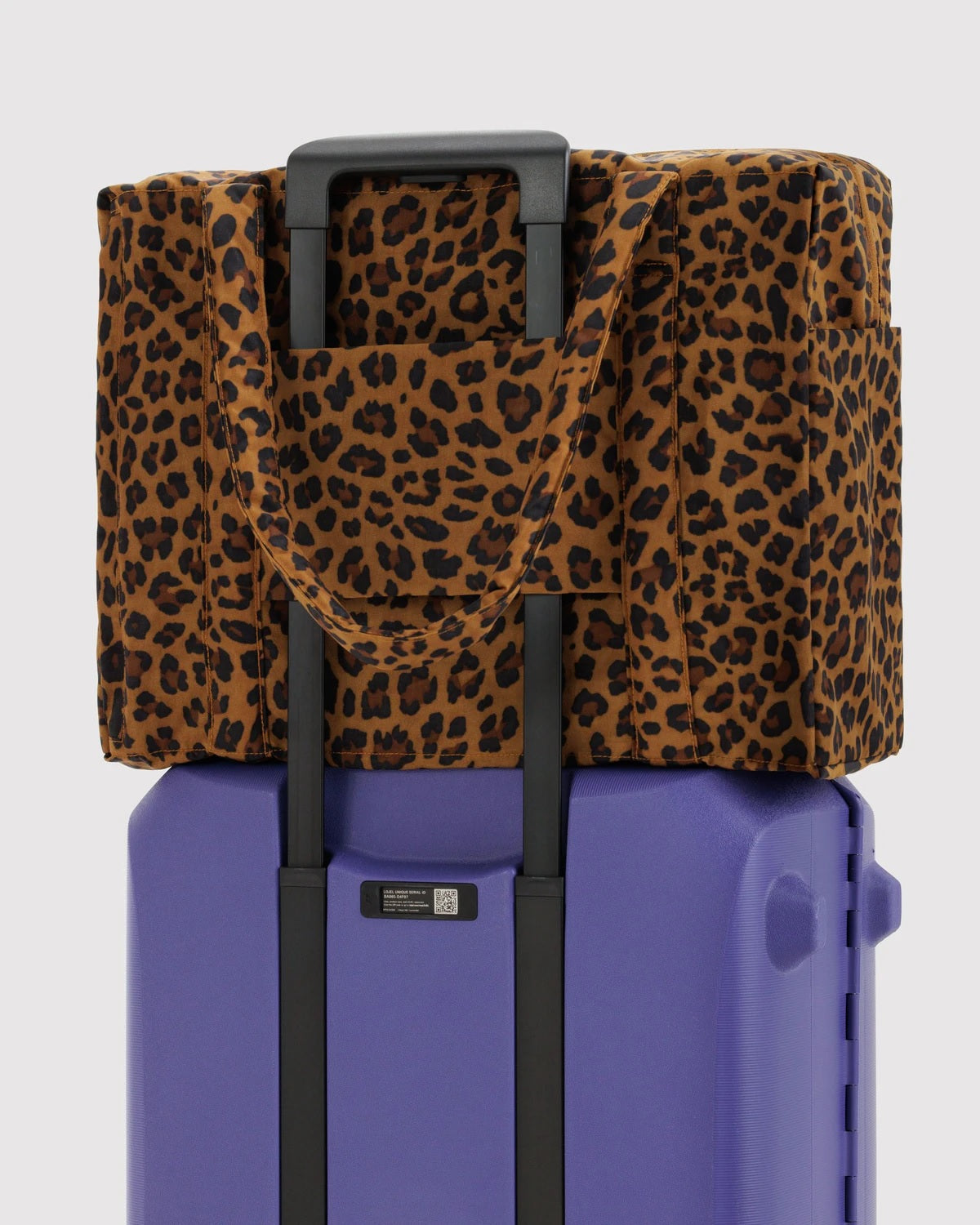 Carry-on bag with leopard print fabric, showing front pocket and shoulder straps