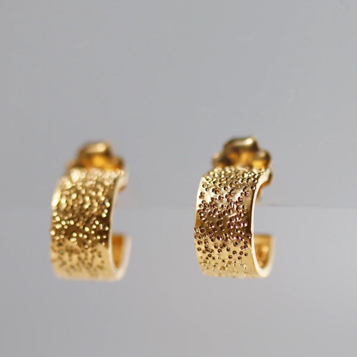 Diamond-dusted gold huggie hoops with textured outer edge and back post