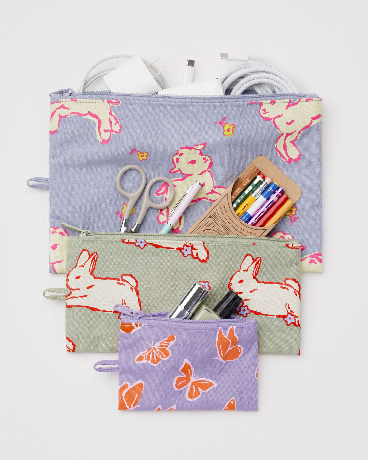 Set of three flat zipper pouches with bunny and butterfly prints, with school supplies inside