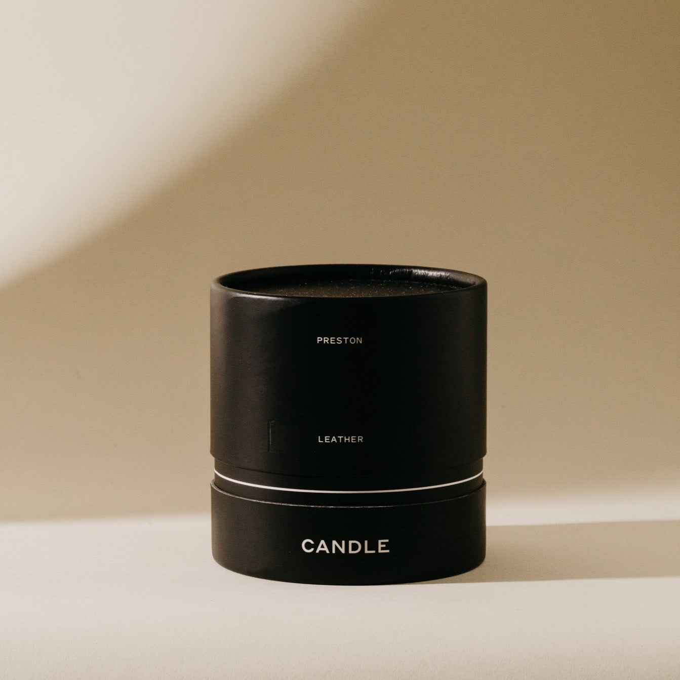Leather candle in black cylindrical jar with centered label details