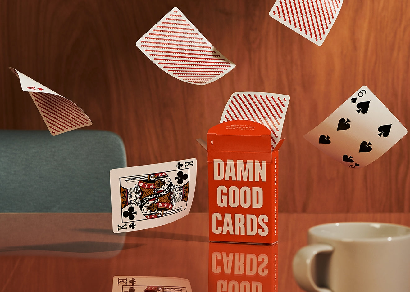 Orange playing card deck box with several scattered cards on a tabletop
