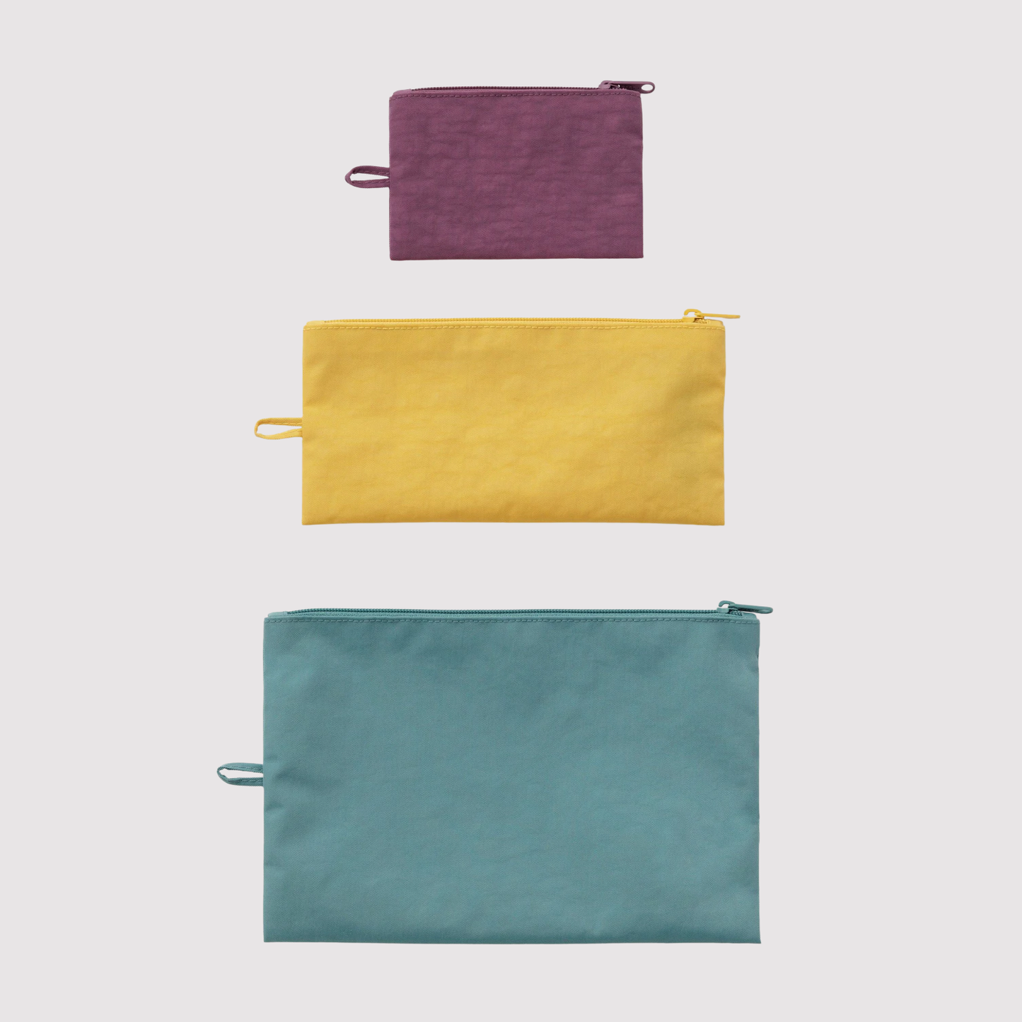 Set of three flat solid-color zipper pouches in plum, yellow, and teal