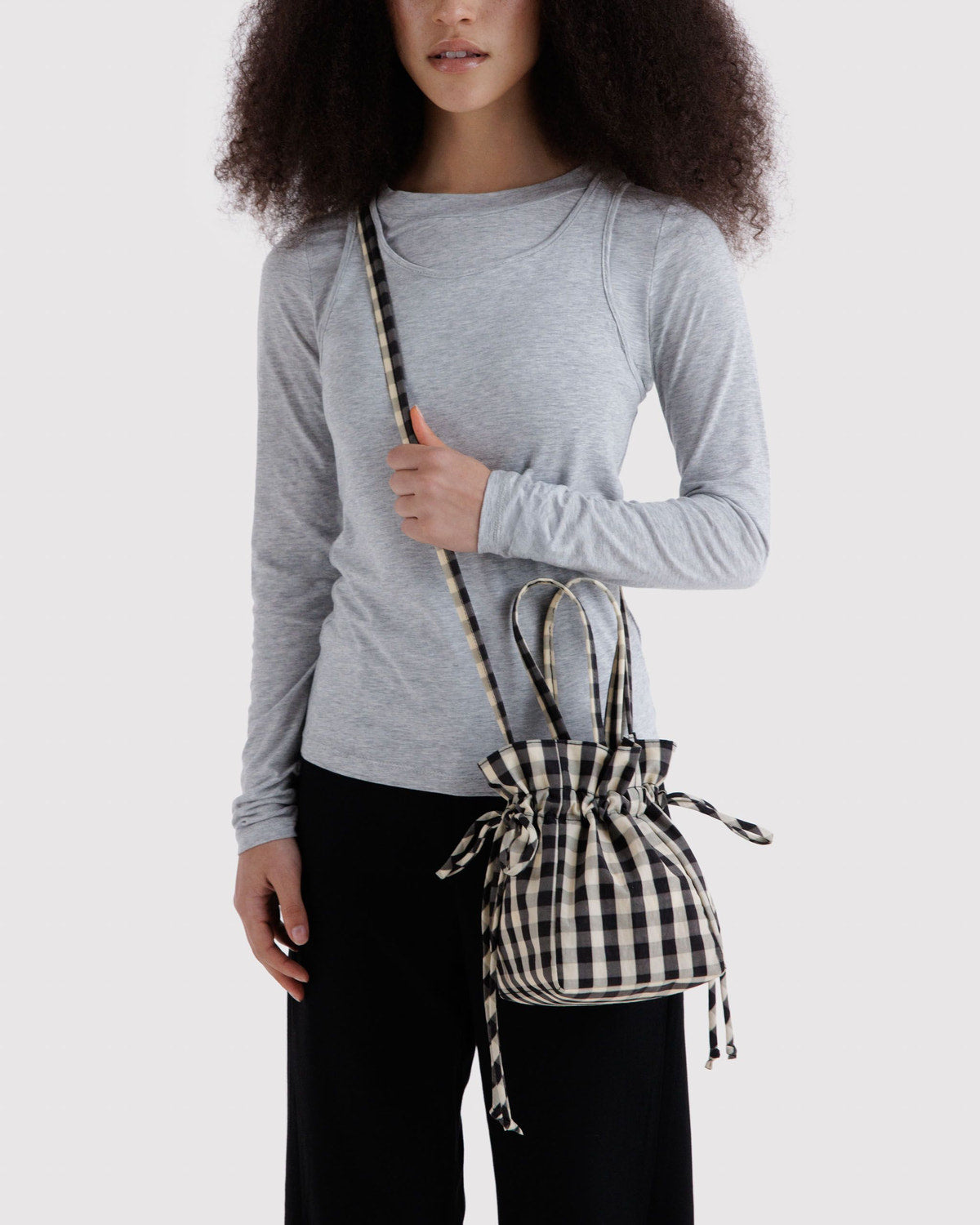 Black and cream check nylon drawstring bag with tied cords, worn crossbody