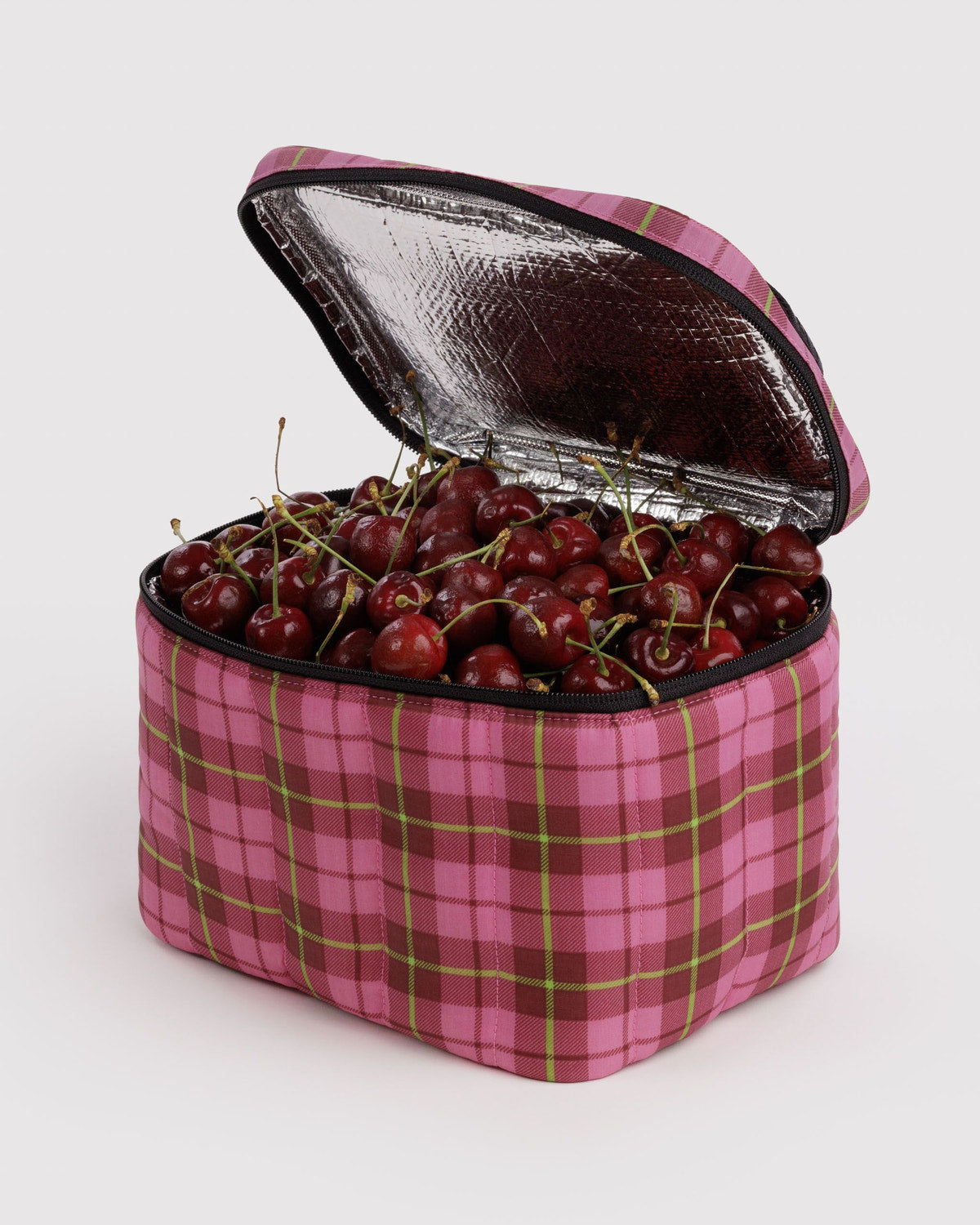 Puffy lunch bag with open foil-lined top, pink plaid fabric with cherries inside.